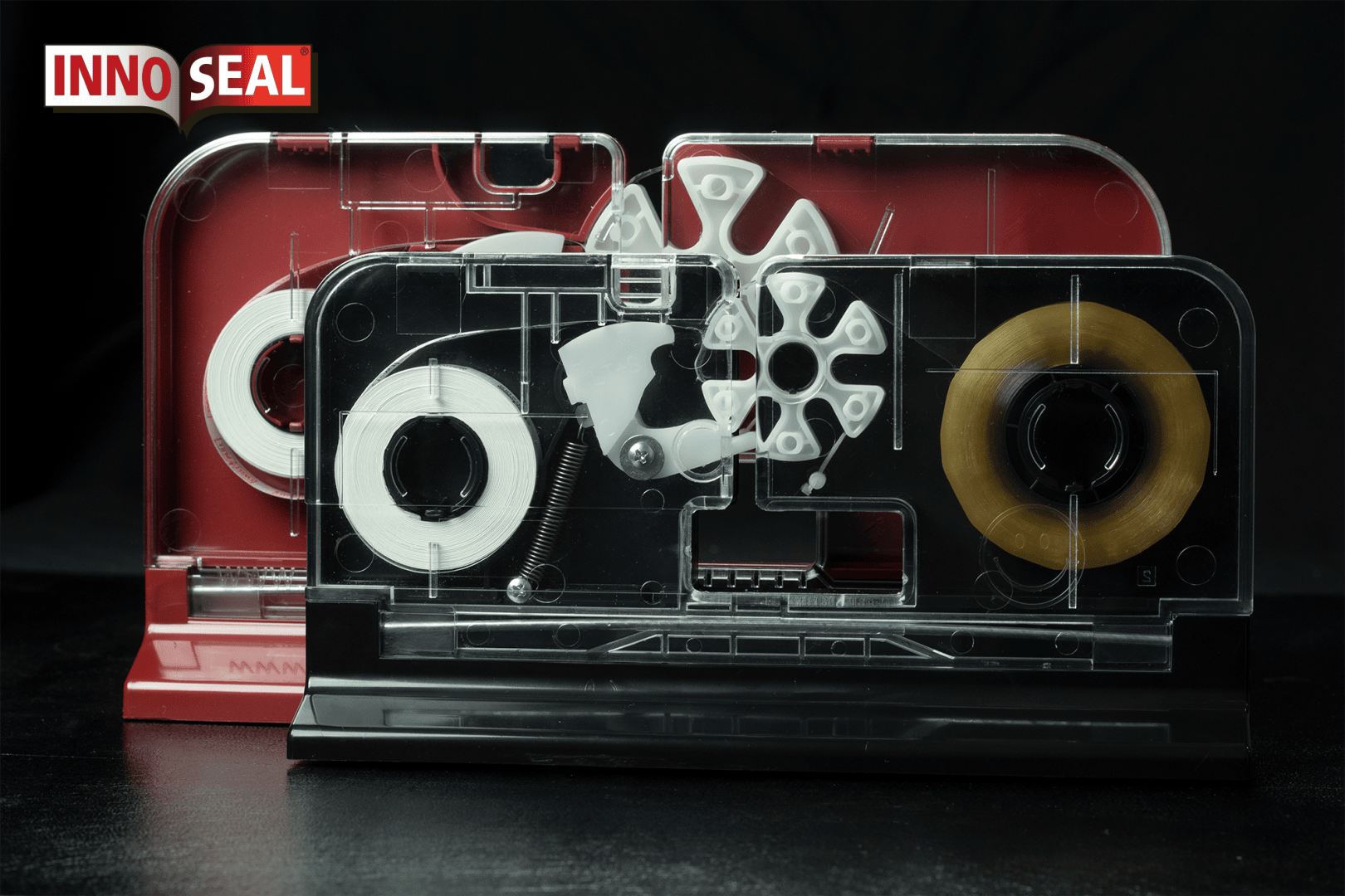 Two INNOSEAL machines with transparent covers reveal internal gears and tape rolls; one has a red base, the other black, and the INNOSEAL logo appears in the top left corner on a black background.