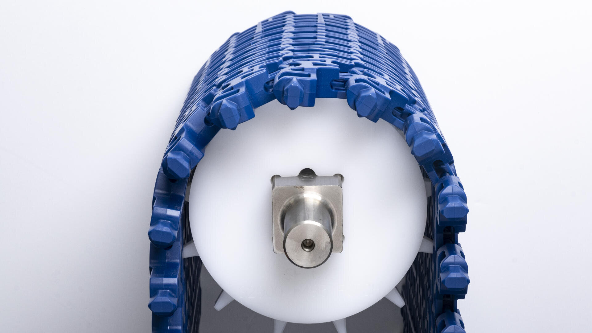 A close-up view of a cylindrical white industrial roller with a blue modular plastic conveyor belt wrapped around it, against a plain white background.