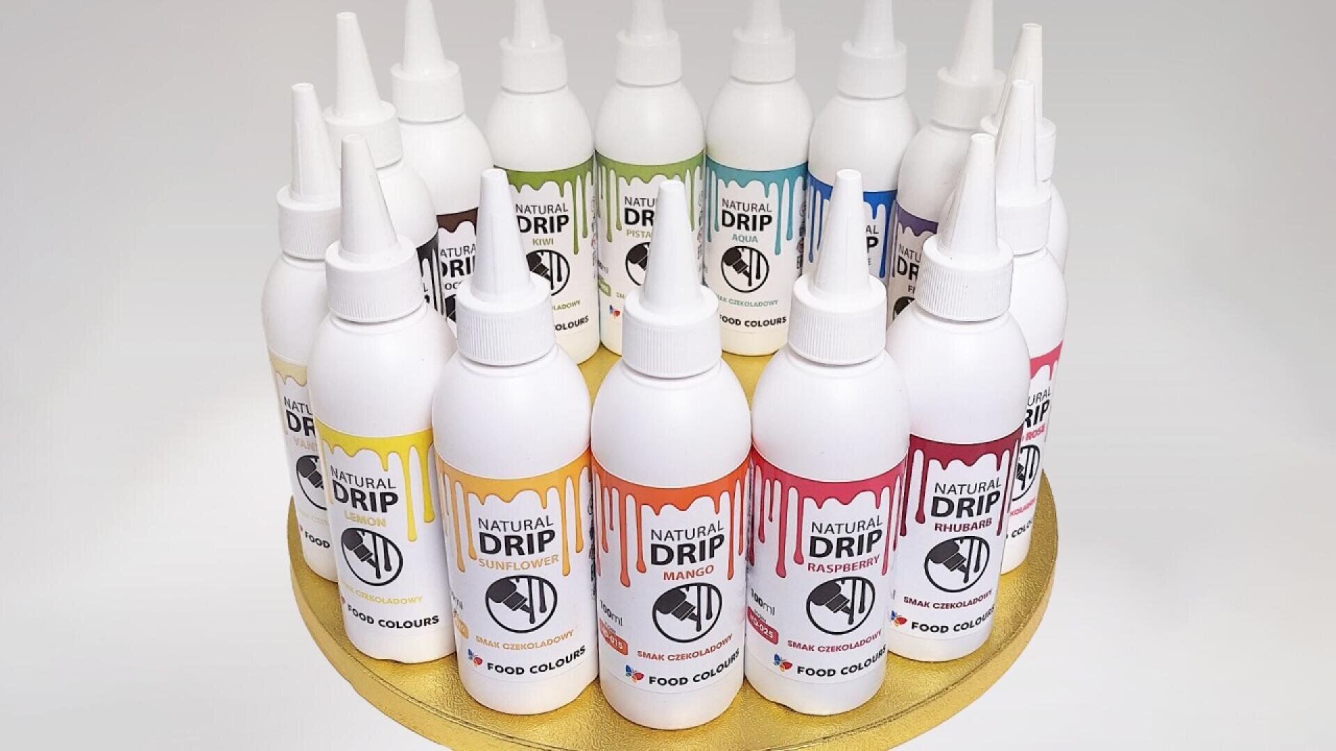 Ein kreisförmiges Display mit bunten Natural Drip Lebensmittelfarbflaschen mit spitzen Kappen, die auf einem goldenen Tablett angeordnet sind. Jedes Etikett zeigt eine andere Geschmacksrichtung, darunter Mango, Himbeere und Orange.
