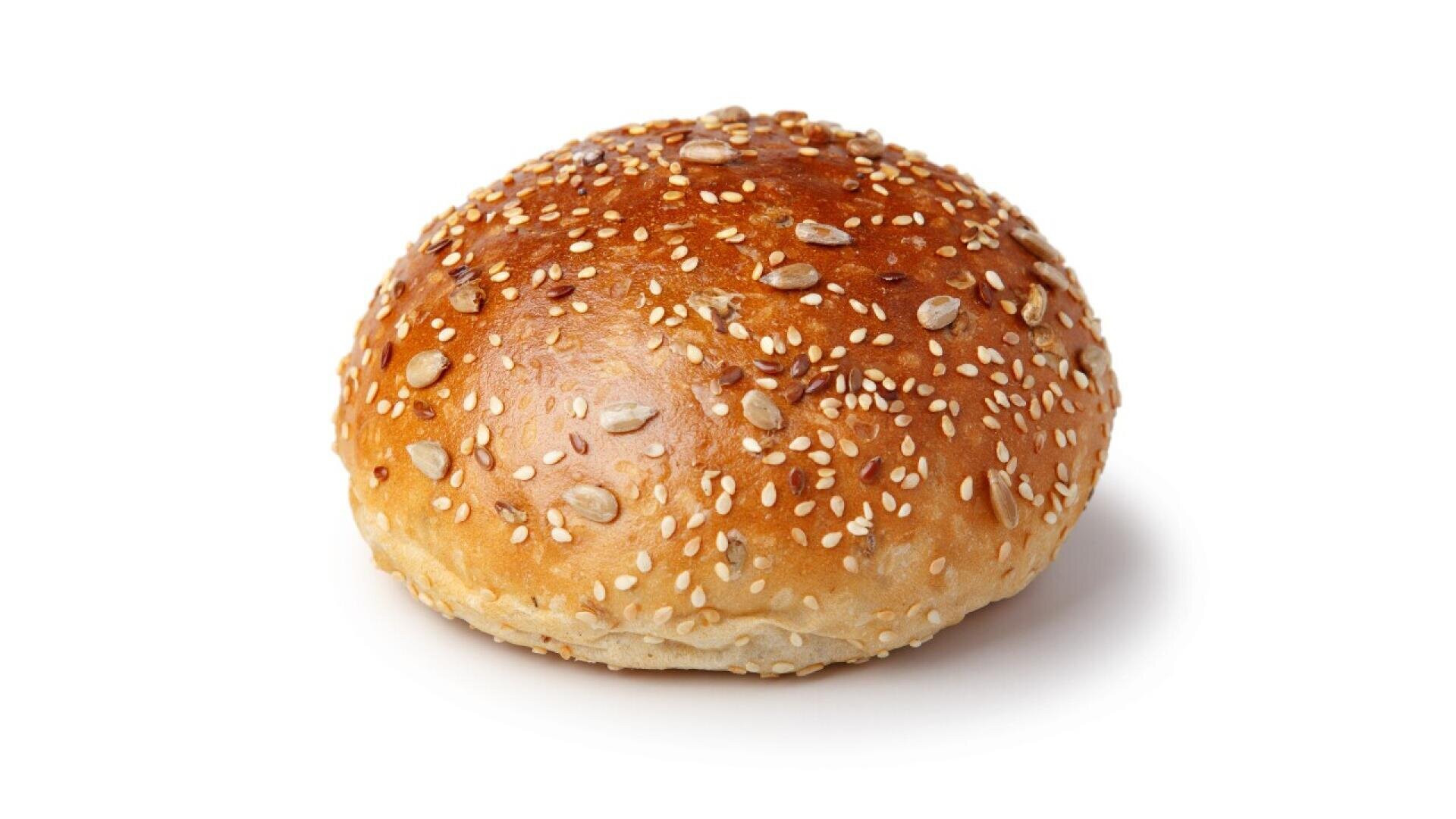A round sesame seed bun with a shiny, golden-brown crust, sprinkled with sesame and sunflower seeds, isolated on a white background.
