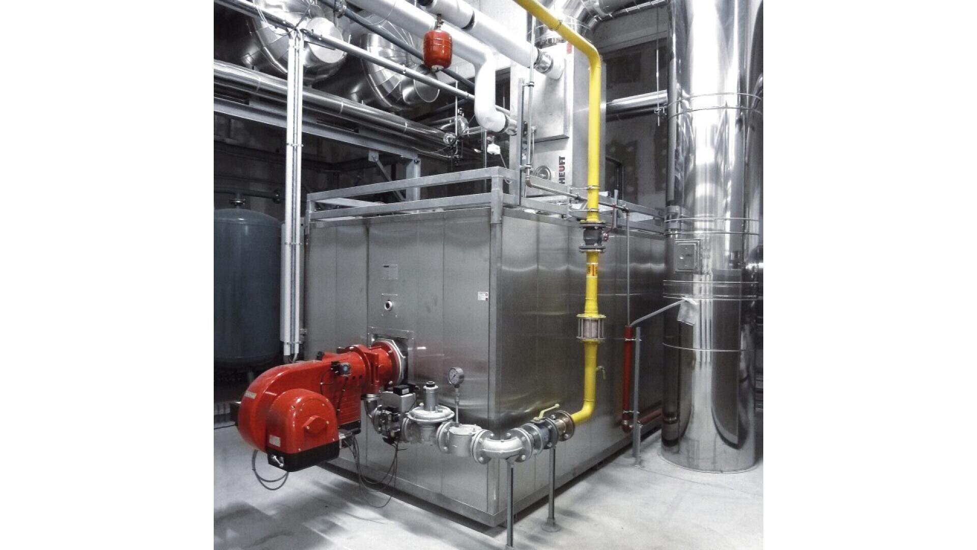 Industrial boiler system with metallic pipes, a yellow gas line, a red burner, and various controls, located inside a utility room with reflective steel surfaces and connected equipment.