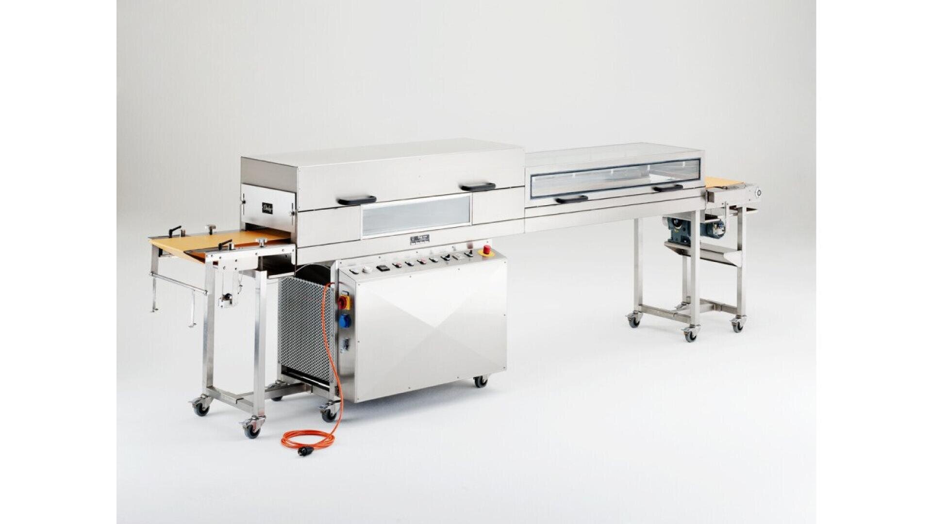 A stainless steel industrial conveyor oven with control panel, glass viewing window, wheels, and an orange power cord, set against a plain white background.
