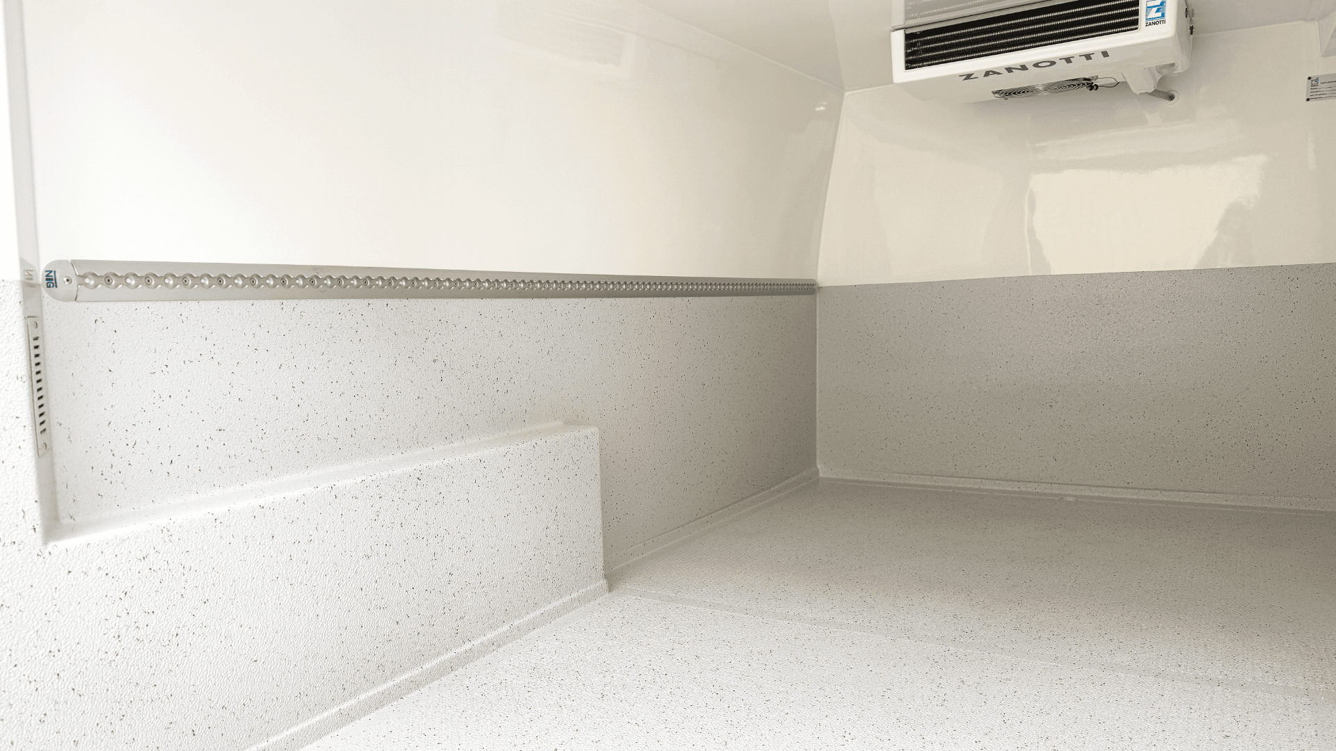 Innenraum eines leeren Kühltransporters mit sauberen, weiß gesprenkelten Wänden und Böden, Metallgeländer entlang der Wand und ein an der Decke montiertes Zanotti-Kühlgerät.