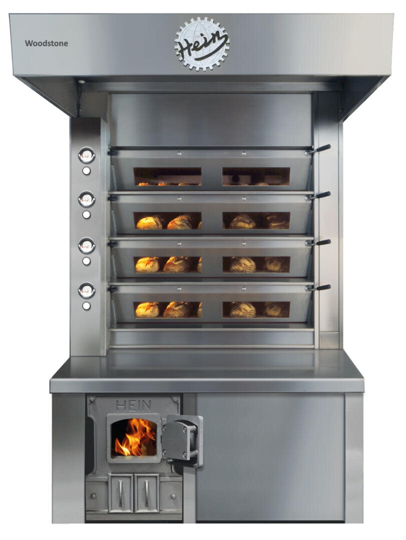 Ein kommerzieller Brotofen aus Edelstahl mit vier gestapelten Regalen, die mit Broten gefüllt sind. Der Ofen hat sichtbare Temperaturregler auf der linken Seite und ein Feuer, das in einem kleinen Fach unten links brennt.