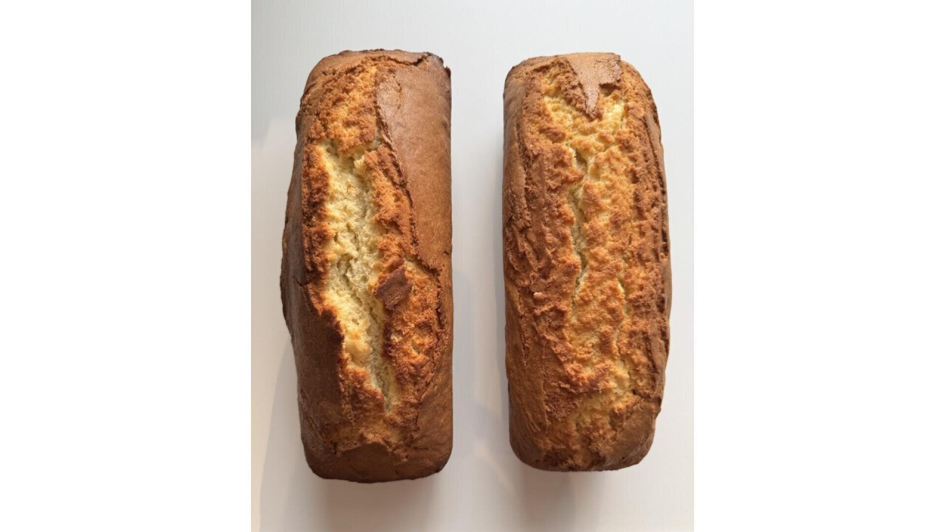 Zwei goldbraune Brotlaibe mit rissiger, strukturierter Oberfläche liegen nebeneinander auf einer weißen Fläche. Die Laibe sehen aus wie frisch gebacken und wirken rustikal und hausgemacht.