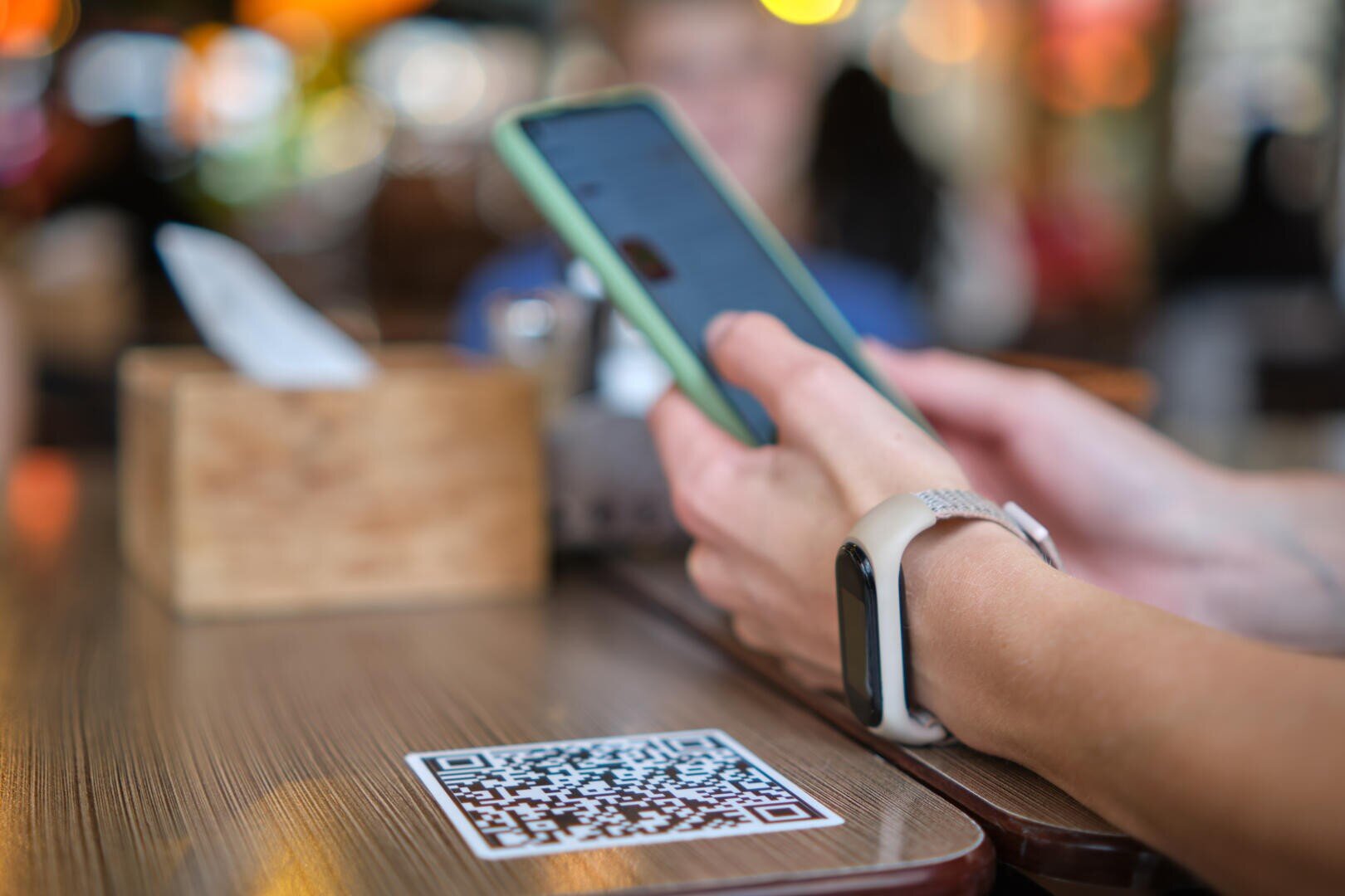 Closeup of guest hand ordering meal in restaurant while scanning qr code with mobile phone for online menu.