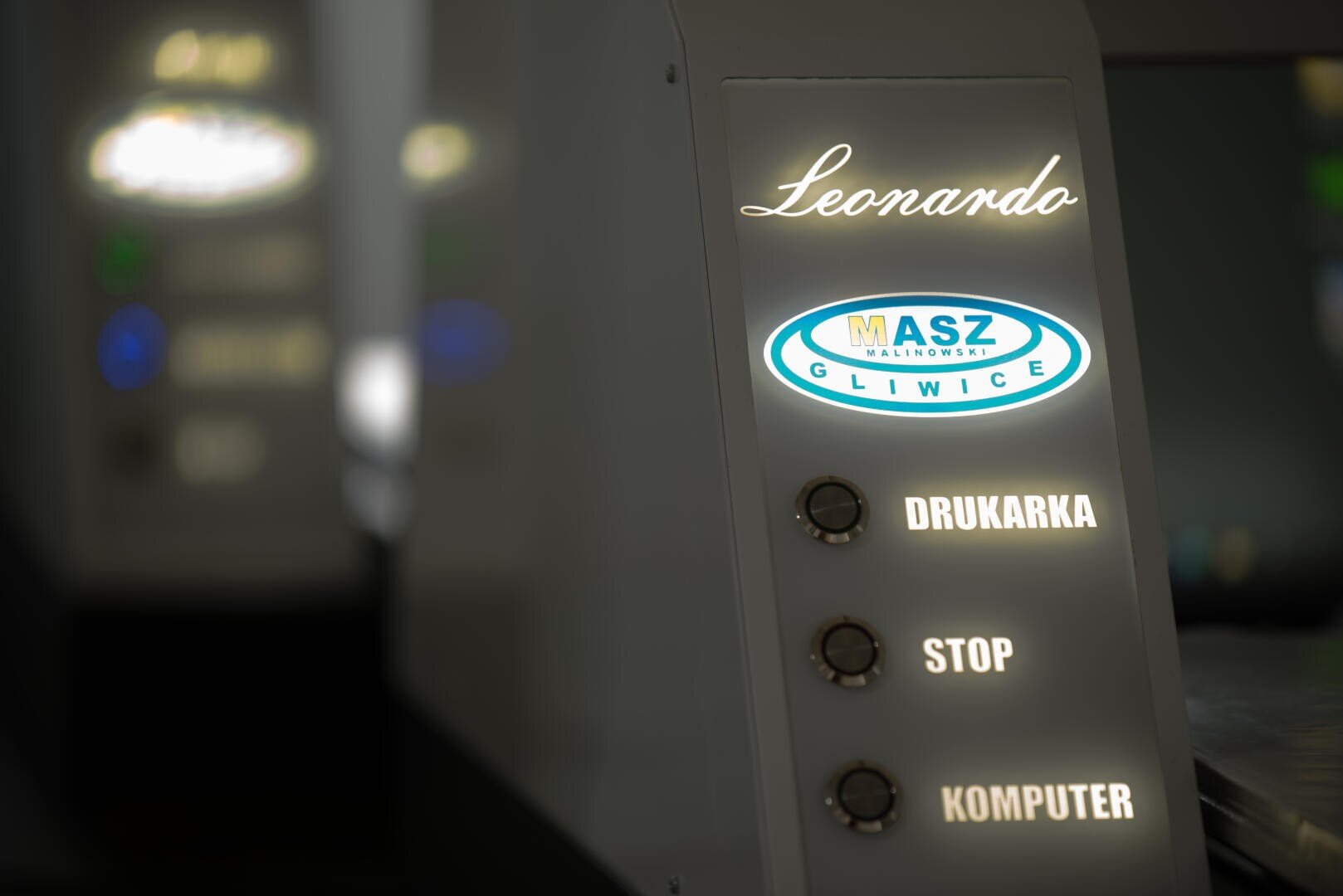 Close-up of a control panel labeled Leonardo with three buttons: DRUKARKA, STOP, and KOMPUTER. An illuminated MASZ GLIWICE logo is displayed above the buttons.