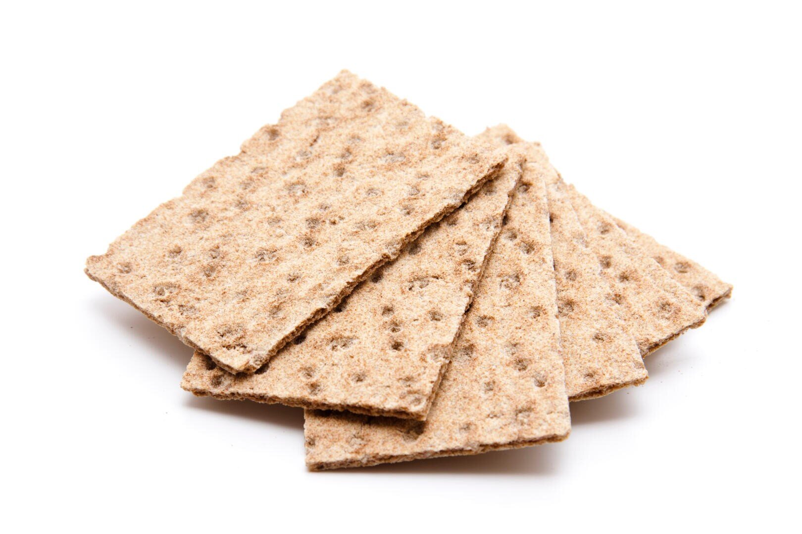 Vier rechteckige Vollkorn-Knäckebrot-Cracker sind leicht schief auf einem weißen Hintergrund gestapelt. Die Cracker sind dünn und haben eine raue, strukturierte Oberfläche mit kleinen Löchern.
