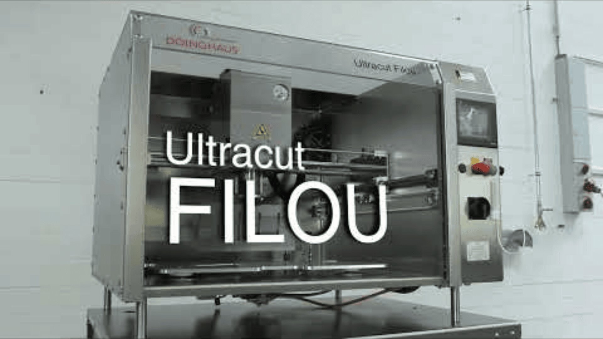 A stainless steel industrial machine labeled Ultracut FILOU with a control panel on the right, manufactured by Döinghaus, is positioned against a white wall in a factory setting.
