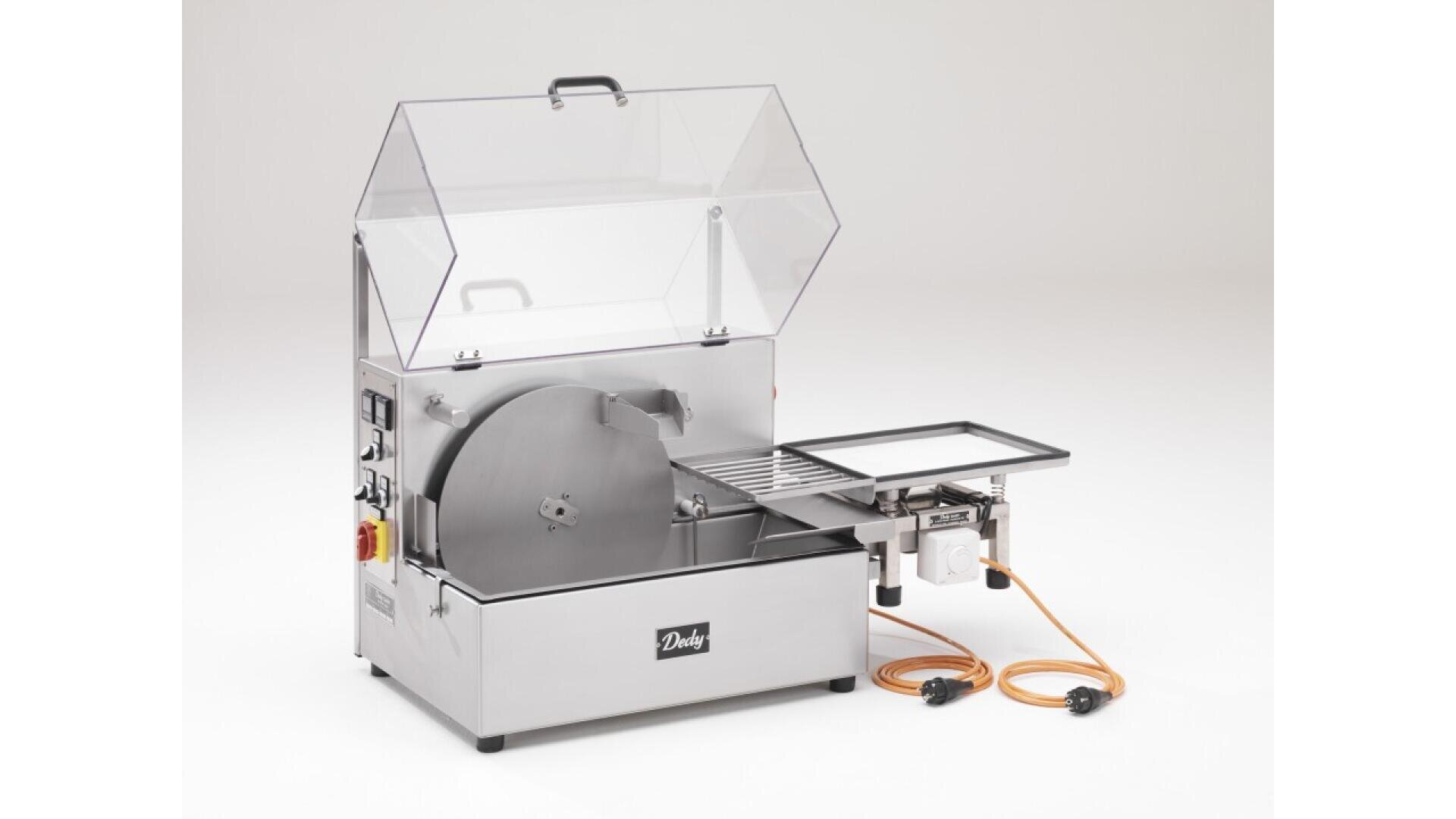 A stainless steel industrial saw with a large circular blade, clear protective cover, control buttons, and orange power cables, designed for precise cutting tasks.