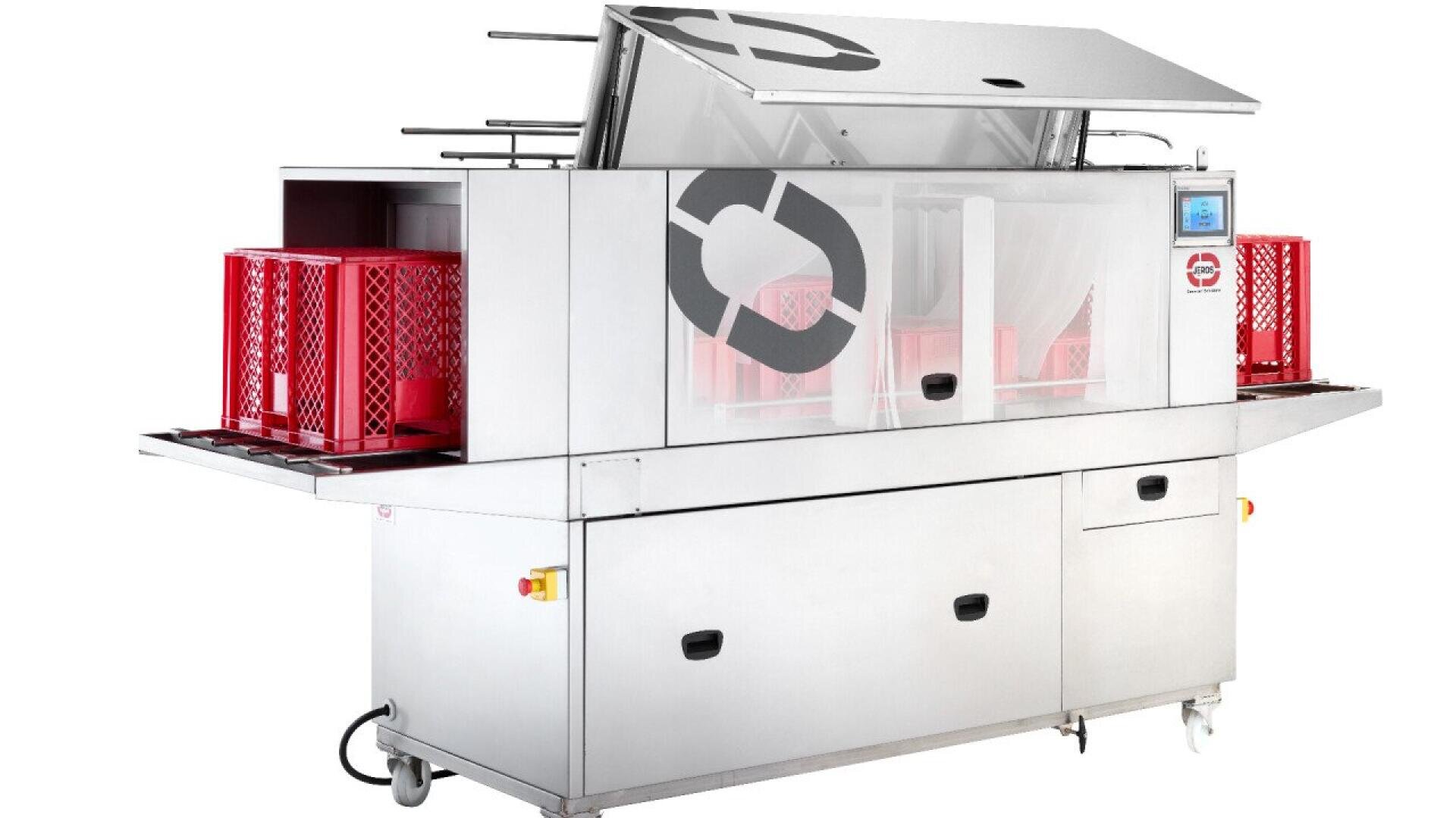 A large industrial machine with a stainless steel exterior, open top lid, and transparent front panel, washing red plastic crates; control panel and buttons are visible on the right side.