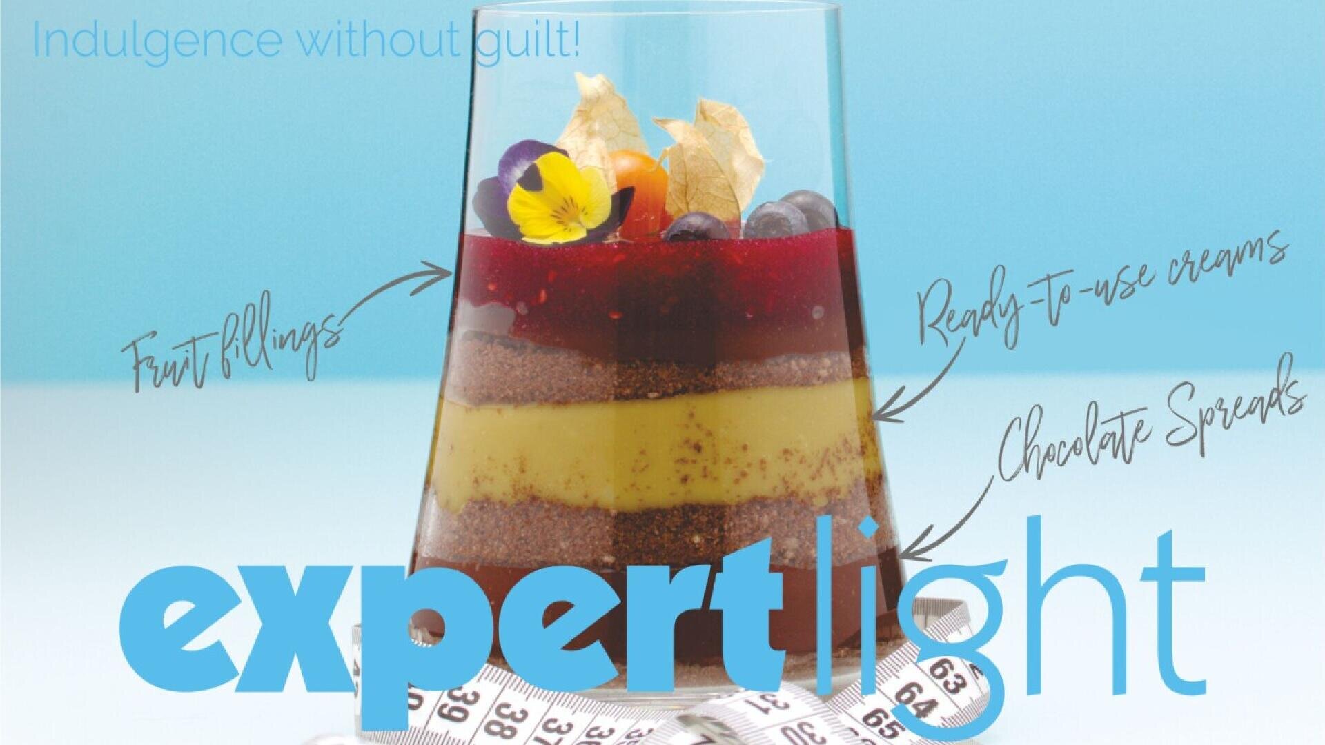 Ein geschichtetes Dessert im Glas mit Früchten, Sahne und Schokolade, gekennzeichnet als Fruchtfüllungen, Fertigcremes und Schokoladenaufstriche. Am Boden ist ein Maßband aufgerollt, der Text lautet: „Genuss ohne Reue!“ und fachmännisches Licht.
