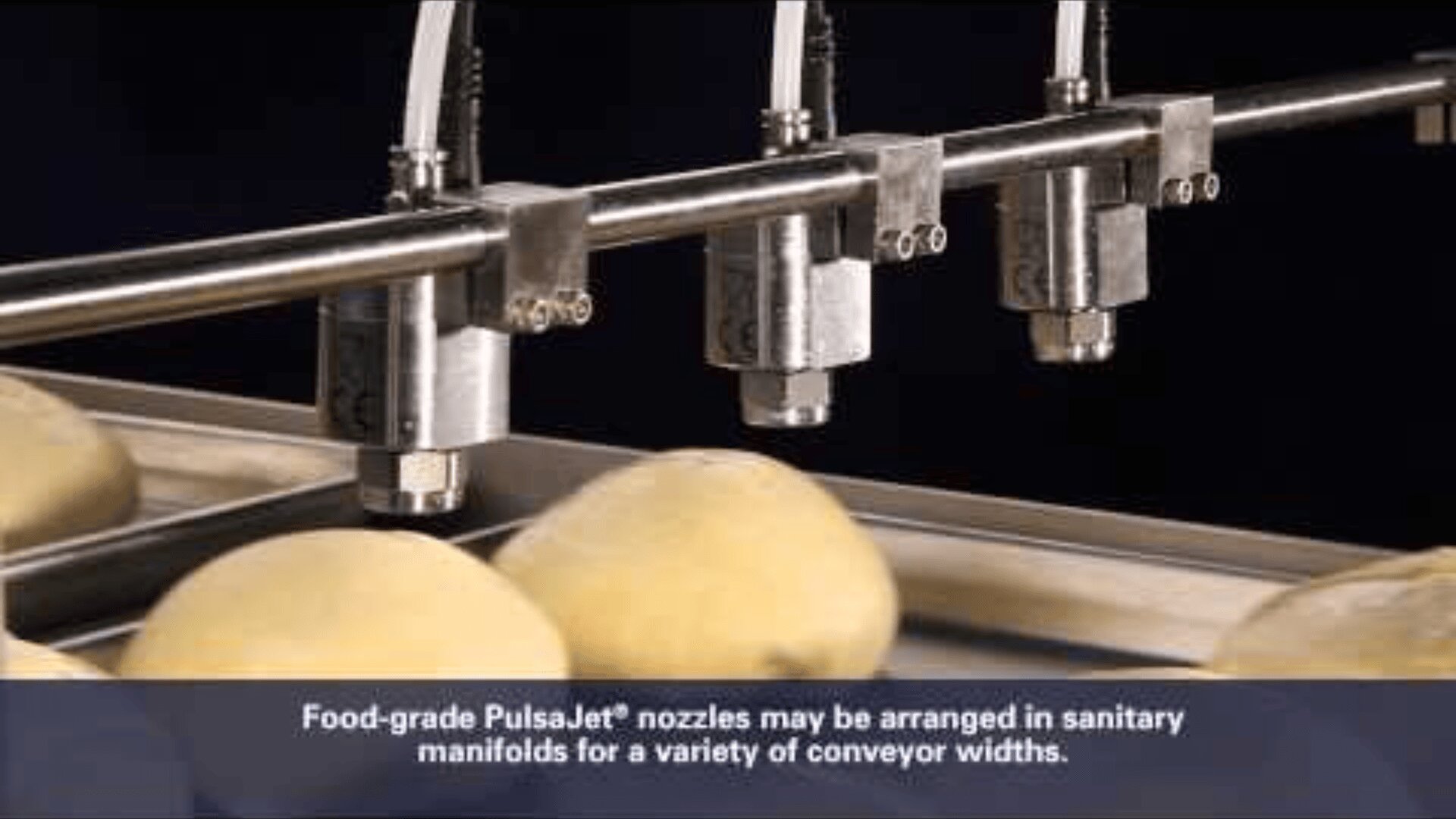 Nahaufnahme von PulsaJet-Düsen in Lebensmittelqualität, die Kartoffeln auf einem Förderband besprühen, mit einer Bildunterschrift, die die Düsenanordnung für unterschiedliche Förderbandbreiten beschreibt.