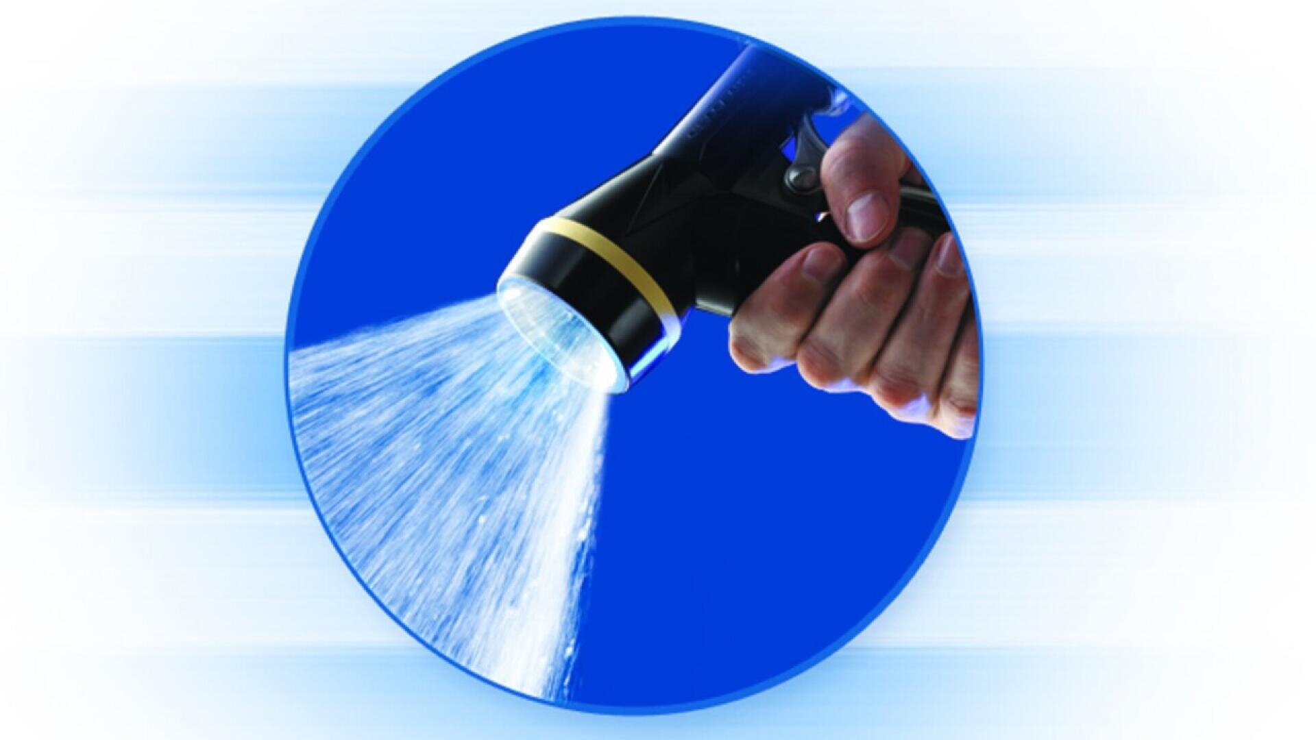 A hand holds a black garden hose nozzle spraying water in a wide stream, set against a blue circular background with light streaks radiating outward.