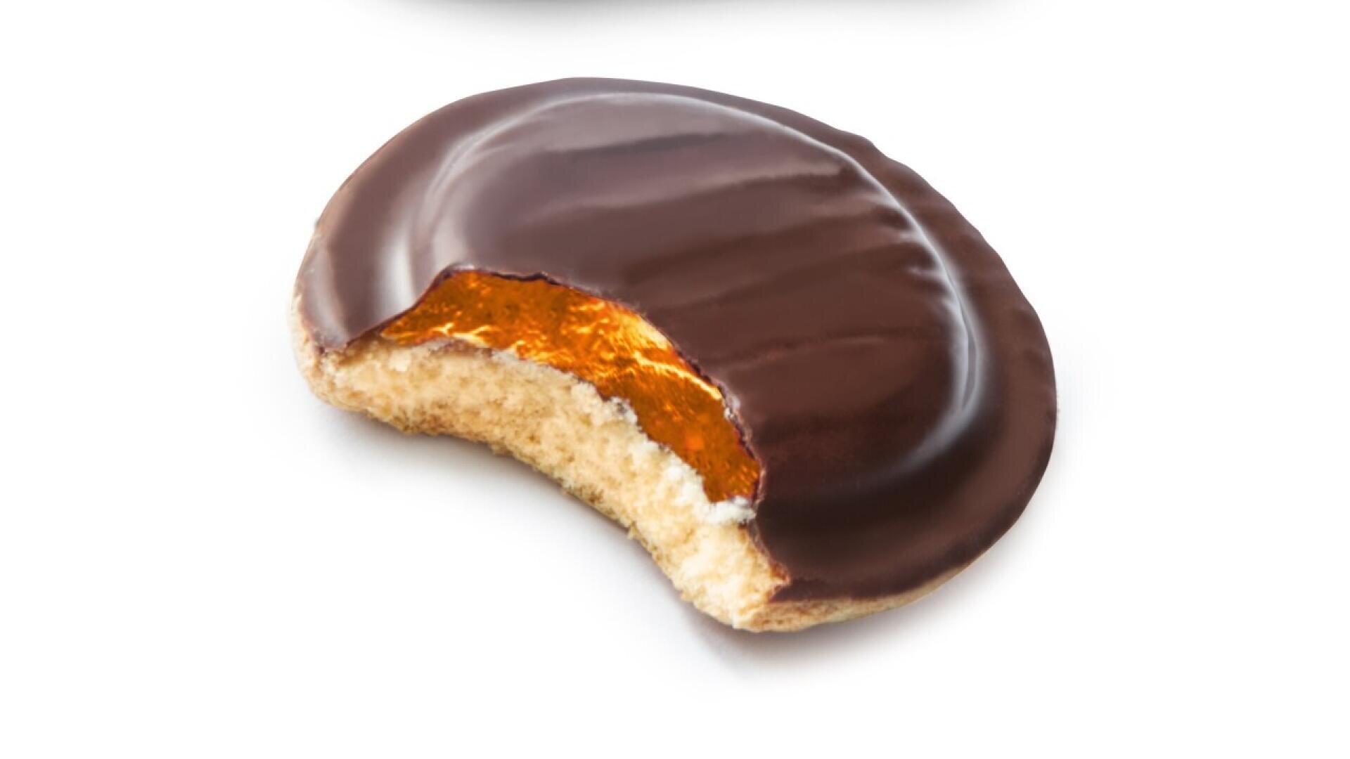 A chocolate-covered biscuit with an orange jelly filling and a bite taken out, revealing the inside layers.