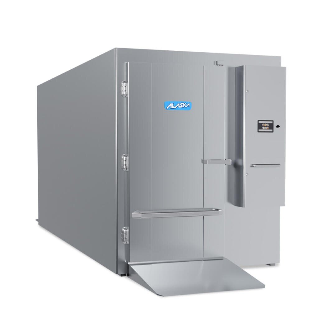 A large industrial walk-in freezer with a closed door, metal ramp, digital control panel, and ALASKA logo on the front. The unit is metallic gray and designed for commercial use.