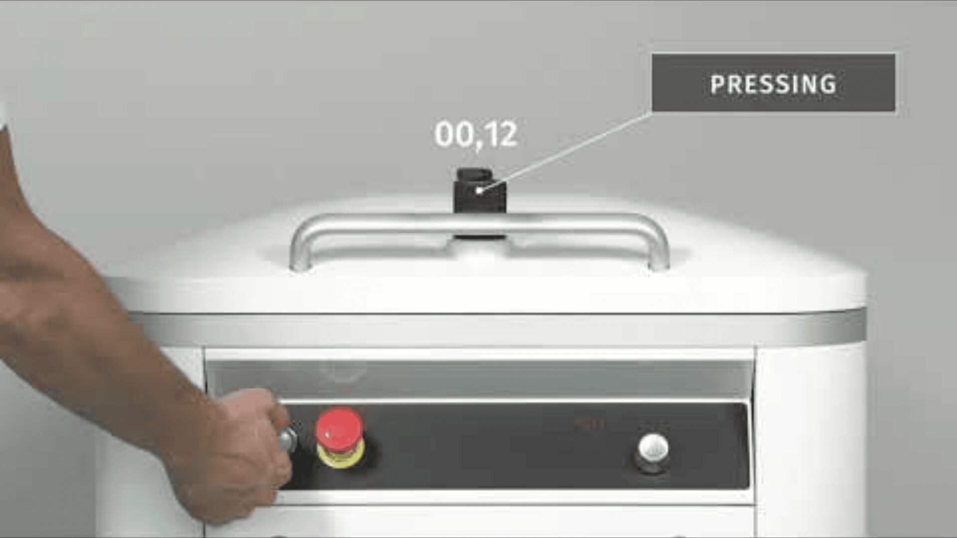 Eine Person drückt einen roten Not-Aus-Knopf an einer weißen Industriemaschine. Eine Zeitschaltuhr über der Maschine zeigt "00,12" an, und auf einem Etikett steht "PRESSING" vor einem schlichten Hintergrund.