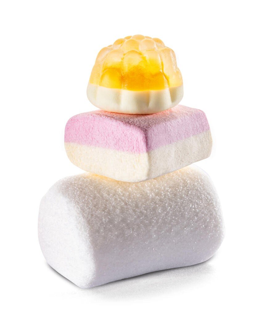 Drei bunte Bonbons übereinander gestapelt: oben ein gelbes und weißes Gummi, in der Mitte ein rosafarbener und weißer, geschichteter Marshmallow und unten ein einfacher weißer, zylindrischer Marshmallow, alles auf weißem Hintergrund.