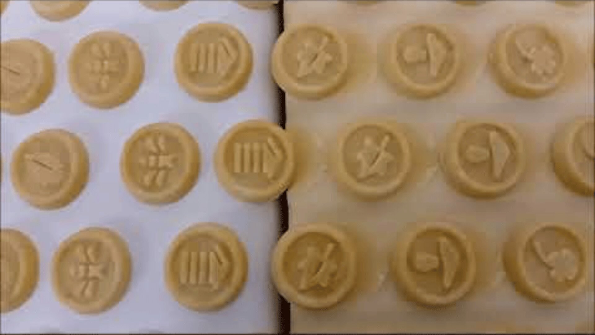 Round cookies are arranged in rows on a light surface, each stamped with various symbols, including hats, stars, and lines. The cookies are unbaked and placed close together in a grid pattern.