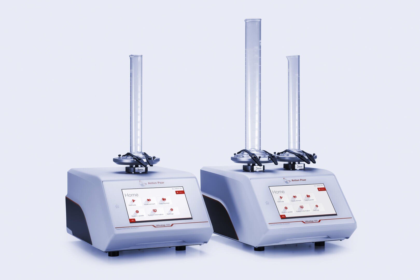 Two identical laboratory devices with digital touchscreens and vertical measurement tubes attached, positioned side by side against a plain white background.