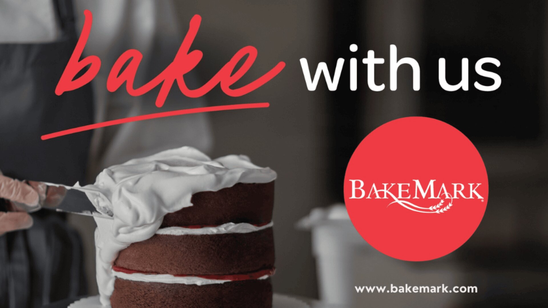A person spreads white frosting on a chocolate layer cake. The text reads “bake with us” and features the BakeMark logo and website URL: www.bakemark.com.