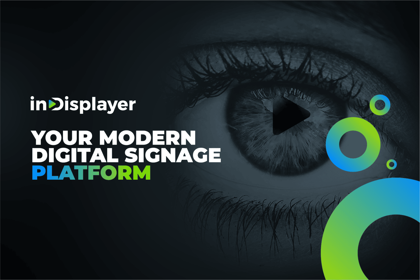 Close-up of a grayscale eye with a play button in the pupil. Text reads: inDisplayER YOUR MODERN DIGITAL SIGNAGE PLATFORM with blue and green circular accents on a dark background.