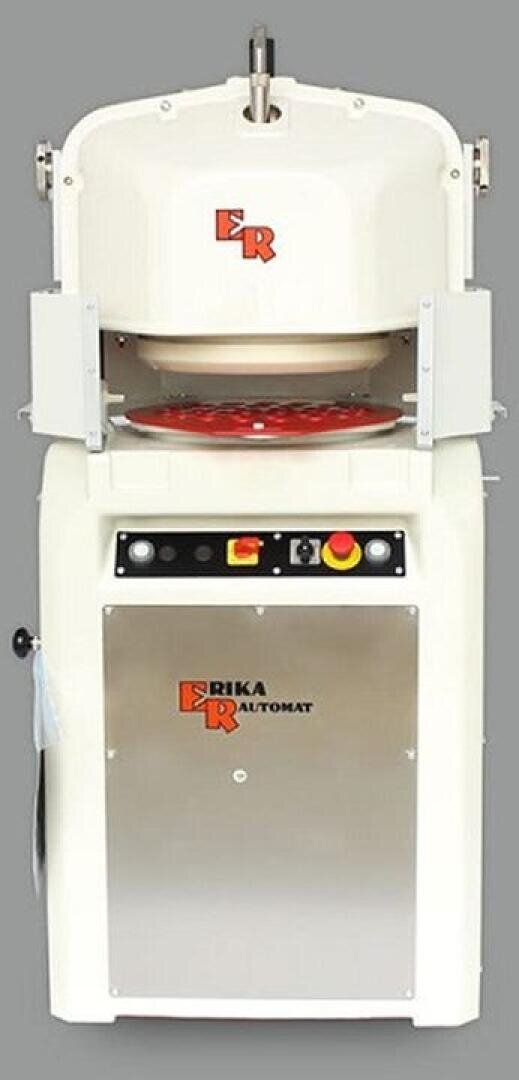 Eine weiß-silberne industrielle Teigteil- und Abrundungsmaschine mit dem Markennamen "Erika" auf der Vorderseite, Bedienknöpfen und einer unteren Metallplatte, dargestellt vor einem schlichten grauen Hintergrund.