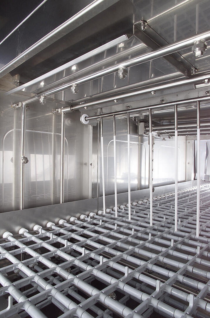 Close-up view of an industrial stainless steel machine interior with rows of metal bars, pipes, and grids, reflecting a clean, modern, and sterile environment, possibly for food or pharmaceutical processing.