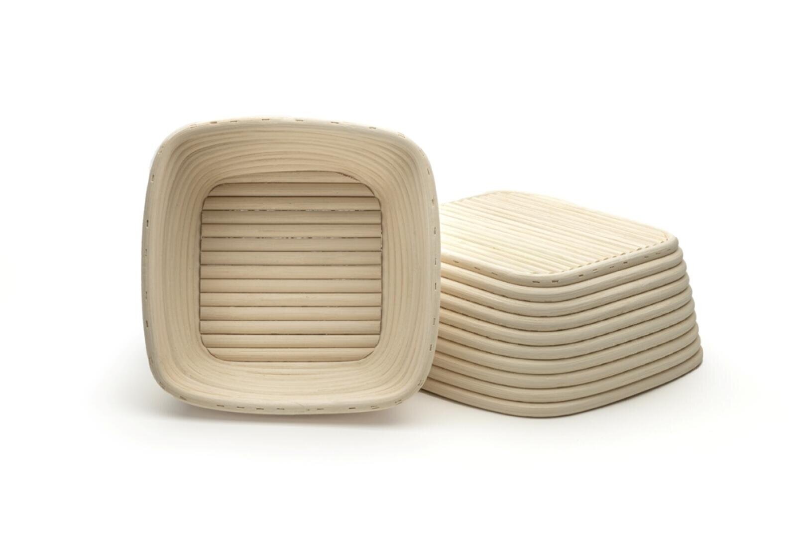 Ein Stapel quadratischer, heller, geflochtener Körbe mit abgerundeten Kanten und horizontalen Rillen auf weißem Hintergrund. Ein Korb steht aufrecht, während die anderen gestapelt sind.