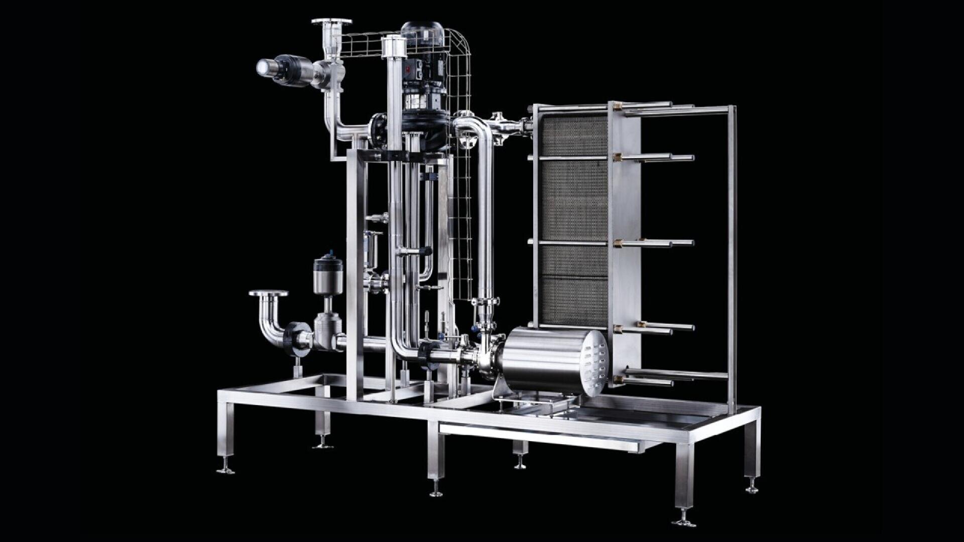 A large industrial stainless steel filtration or processing machine with pipes, valves, and a vertical frame, set against a black background.