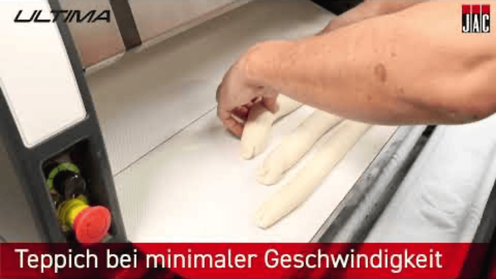 A person places dough rolls onto a conveyor belt in a machine. German text at the bottom reads, Teppich bei minimaler Geschwindigkeit.