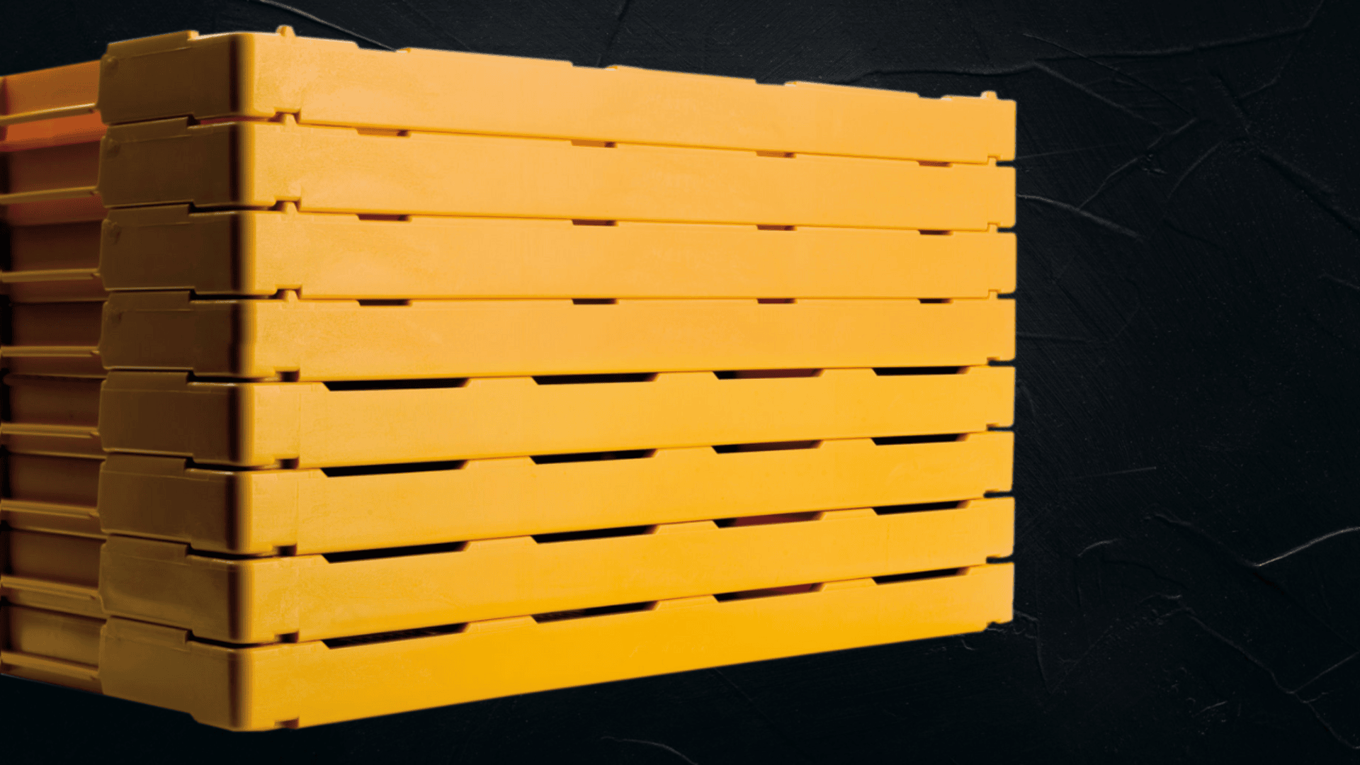 Ein Stapel gelber Plastikkisten ist vor einer dunklen, strukturierten Wand zu sehen, wobei die Kisten horizontale Linien im Bild bilden.