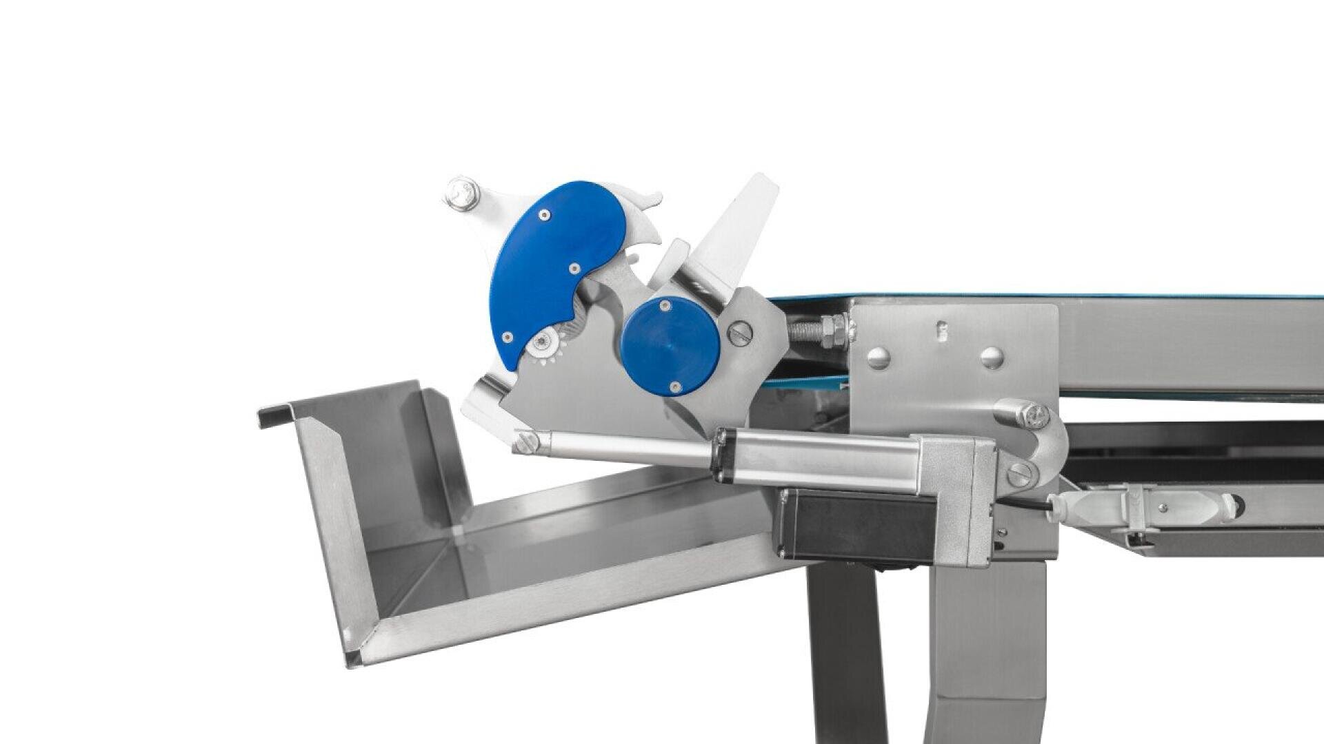 Ein industrielles Fördersystem aus Edelstahl mit einem blauen rotierenden Schneid- oder Führungsmechanismus, der über einem Metalltablett positioniert ist, vor einem weißen Hintergrund.