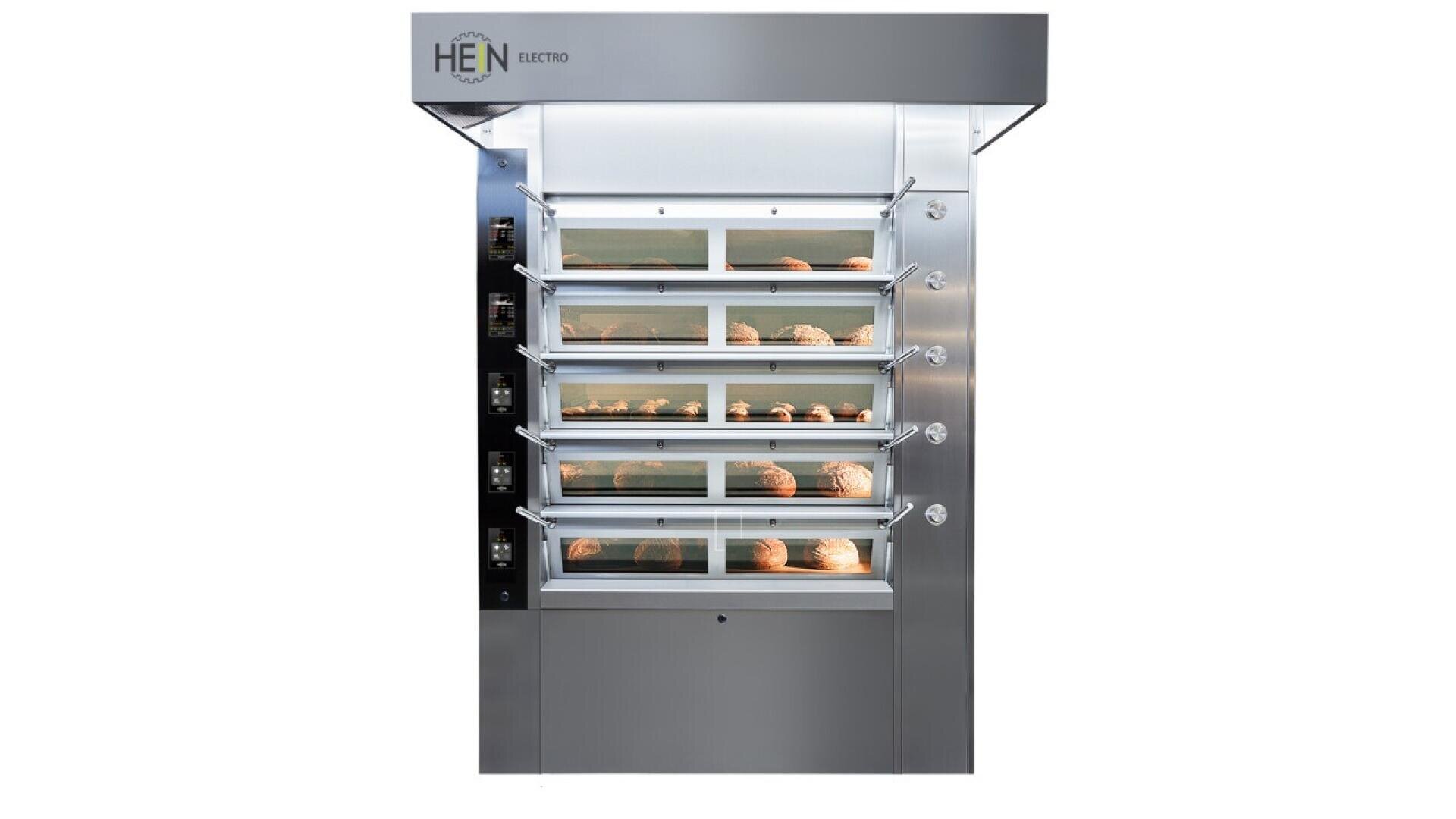 A large stainless steel commercial bread oven with four glass-fronted compartments, each containing multiple loaves of bread, and digital control panels on the side.