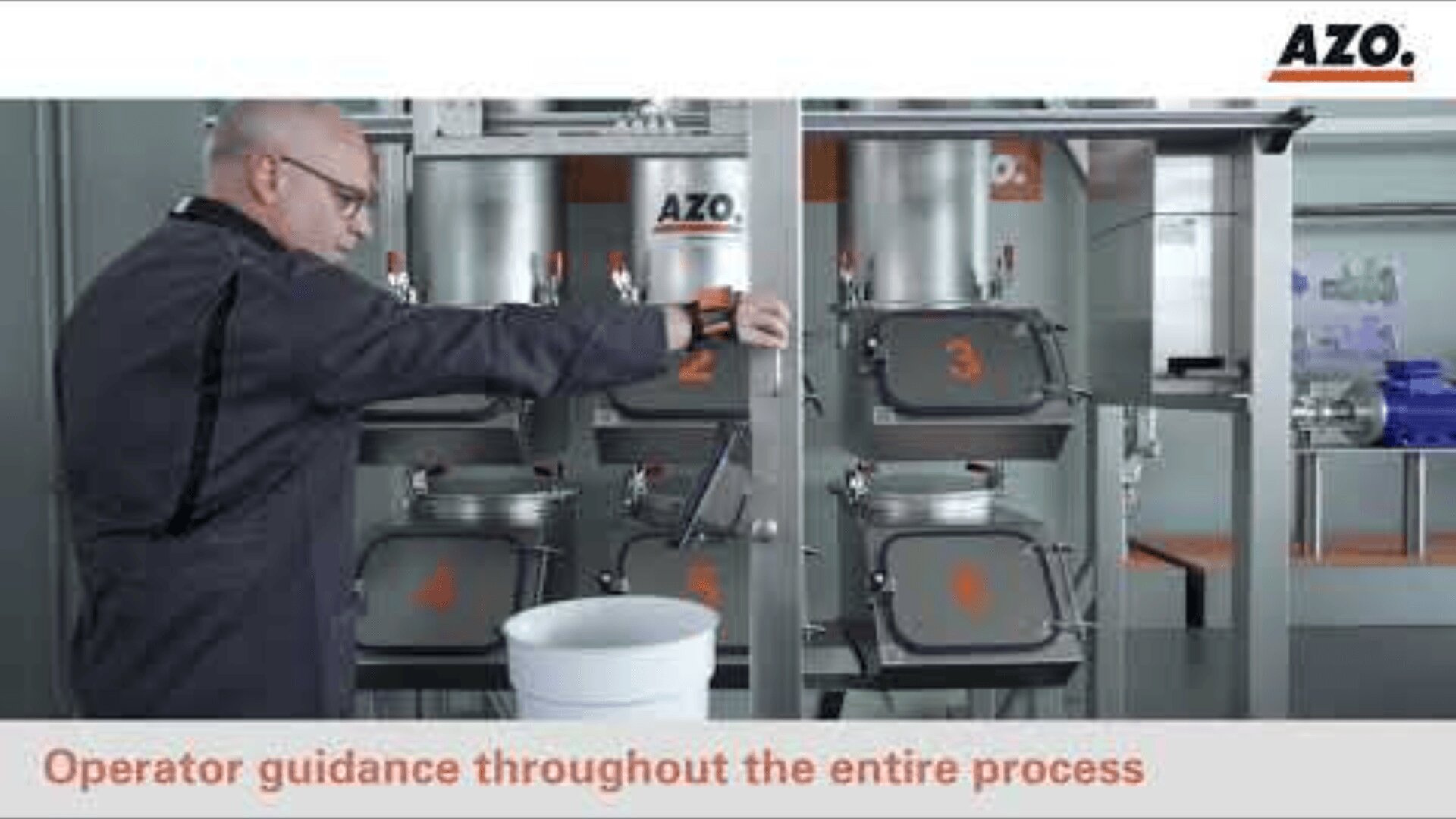 Eine Person bedient Industrieanlagen in einer AZO-Anlage. Sie nutzt ein Bedienfeld in der Nähe von nummerierten Behältern. Davor steht ein weißer Eimer mit dem Text „Bedienungsführung während des gesamten Prozesses“.