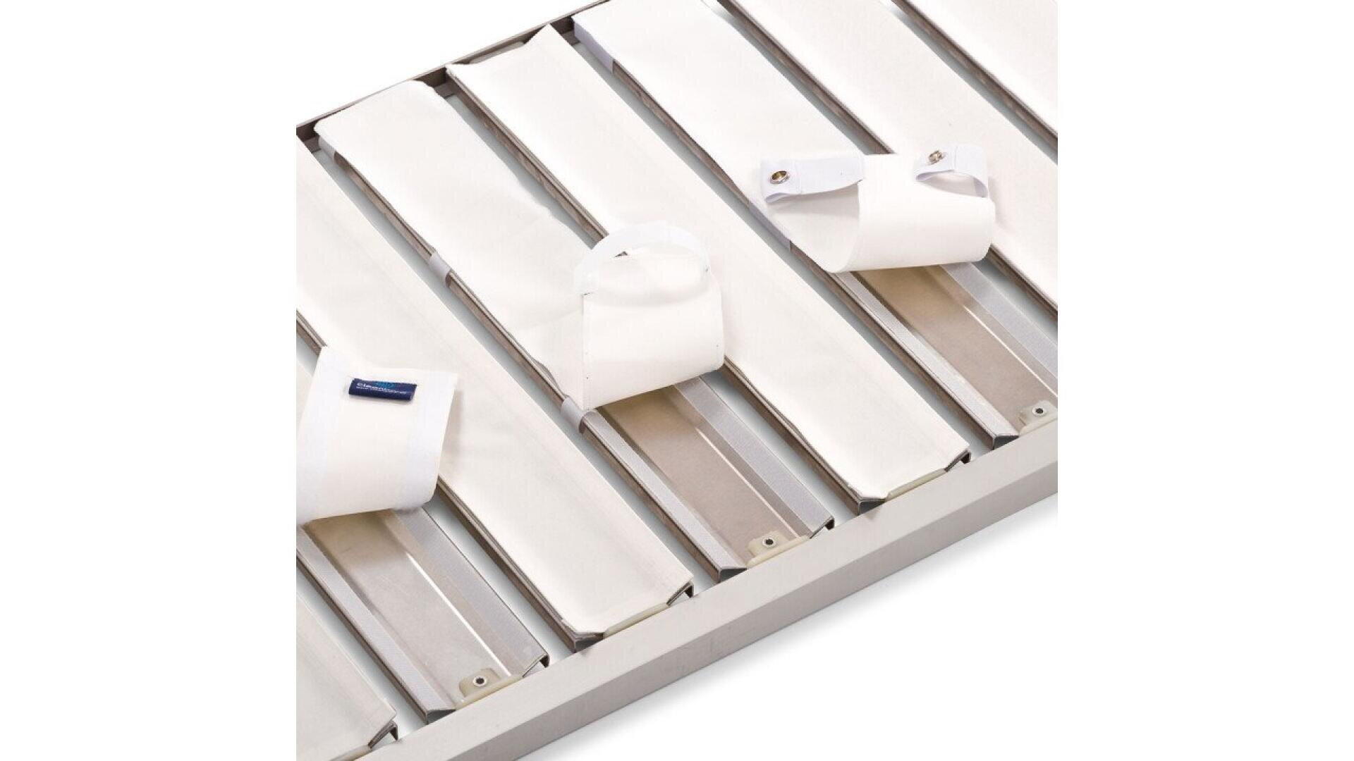 A close-up of a white slatted bed base with three neatly folded white dress shirt cuffs placed on top of the slats.