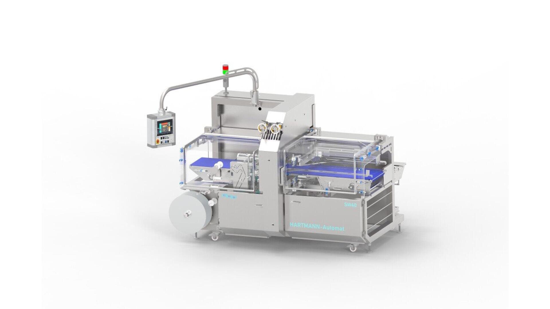 A stainless steel automated packaging machine with control panel, conveyor belts, and clear protective covers, used for wrapping or sealing products. The machine is on wheels and features labeled parts and wiring.