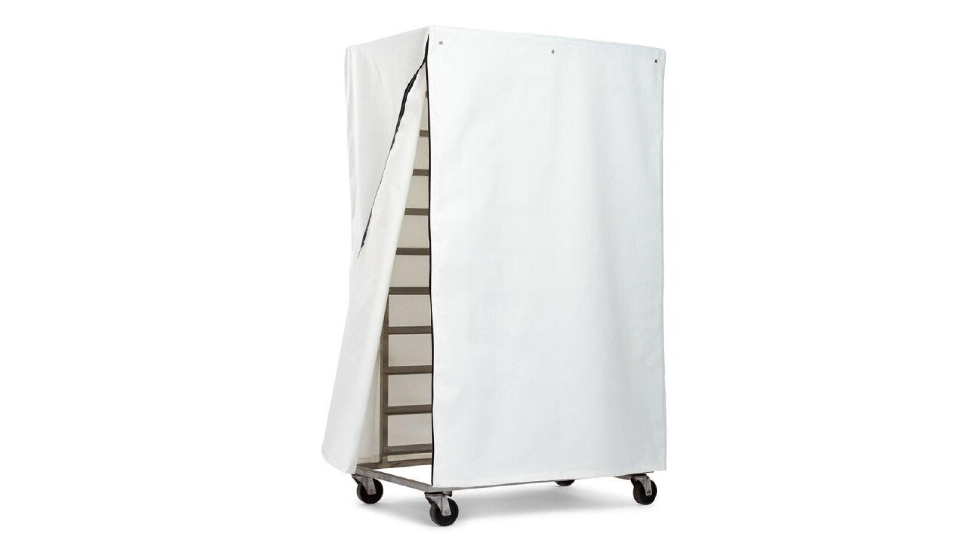 A tall metal rack on wheels covered by a partially open white fabric cover, revealing multiple interior shelves. The rack appears to be used for storage or transport, likely in a commercial kitchen or bakery.