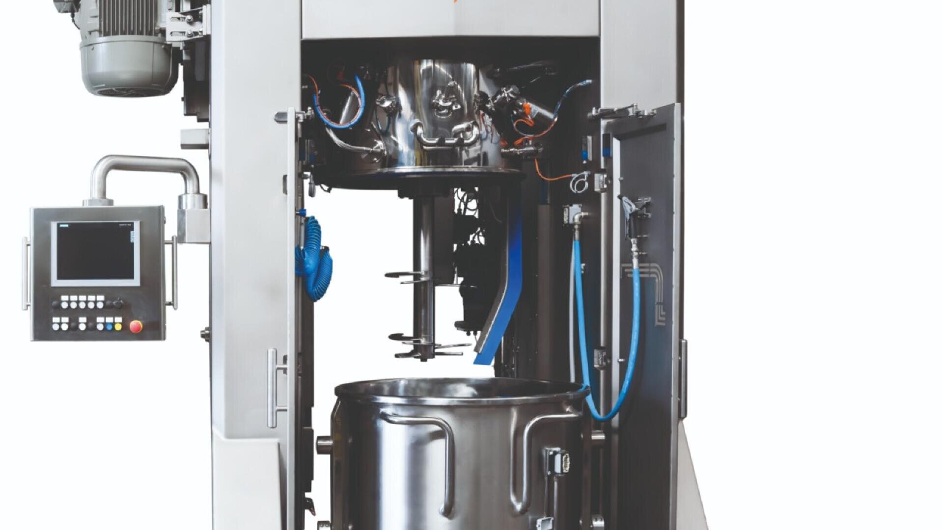 Eine große industrielle Mischmaschine mit einem Bedienfeld auf der linken Seite und einem offenen Fach mit Metallmischflügeln über einem Behälter aus rostfreiem Stahl. Im Inneren der Maschine sind blaue Schläuche und Kabel zu sehen.