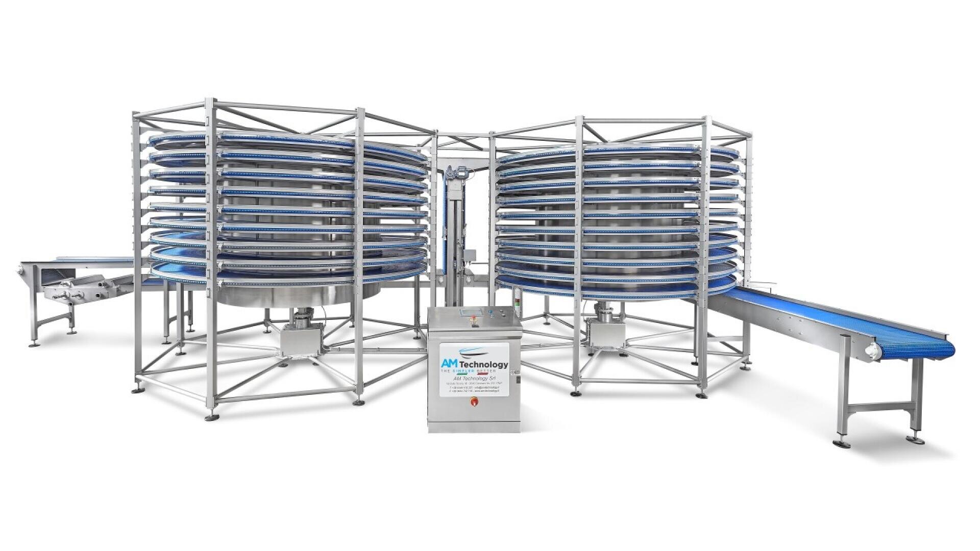 Ein großes industrielles Spiralfördersystem mit blauen Bändern, bestehend aus zwei zylindrischen Spiraltürmen und verbindenden Förderbändern, die alle von einem Metallrahmen getragen werden. In der vorderen Mitte befindet sich ein Steuerpult.