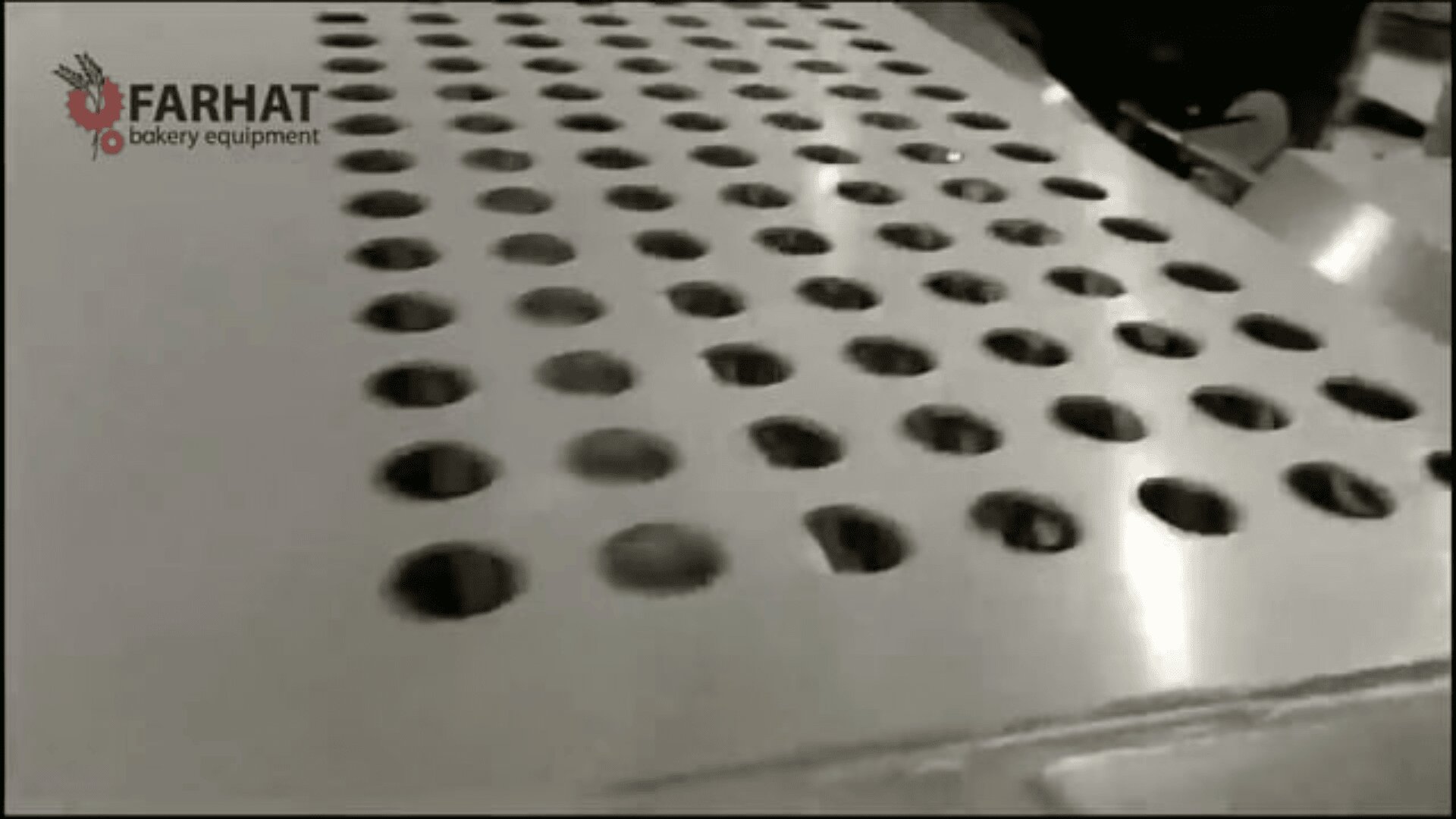 A metal baking tray with multiple round holes, part of industrial bakery equipment, is shown in black and white. The Farhat Bakery Equipment logo appears in the top left corner.