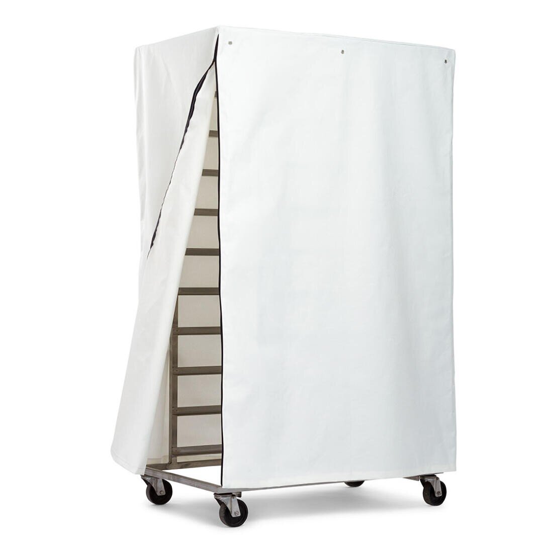 Ein Metallregal auf Rädern ist teilweise mit einer weißen Stoff- oder Vinylhülle bedeckt, die auf einer Seite offen ist, um die Fächer im Inneren freizulegen.