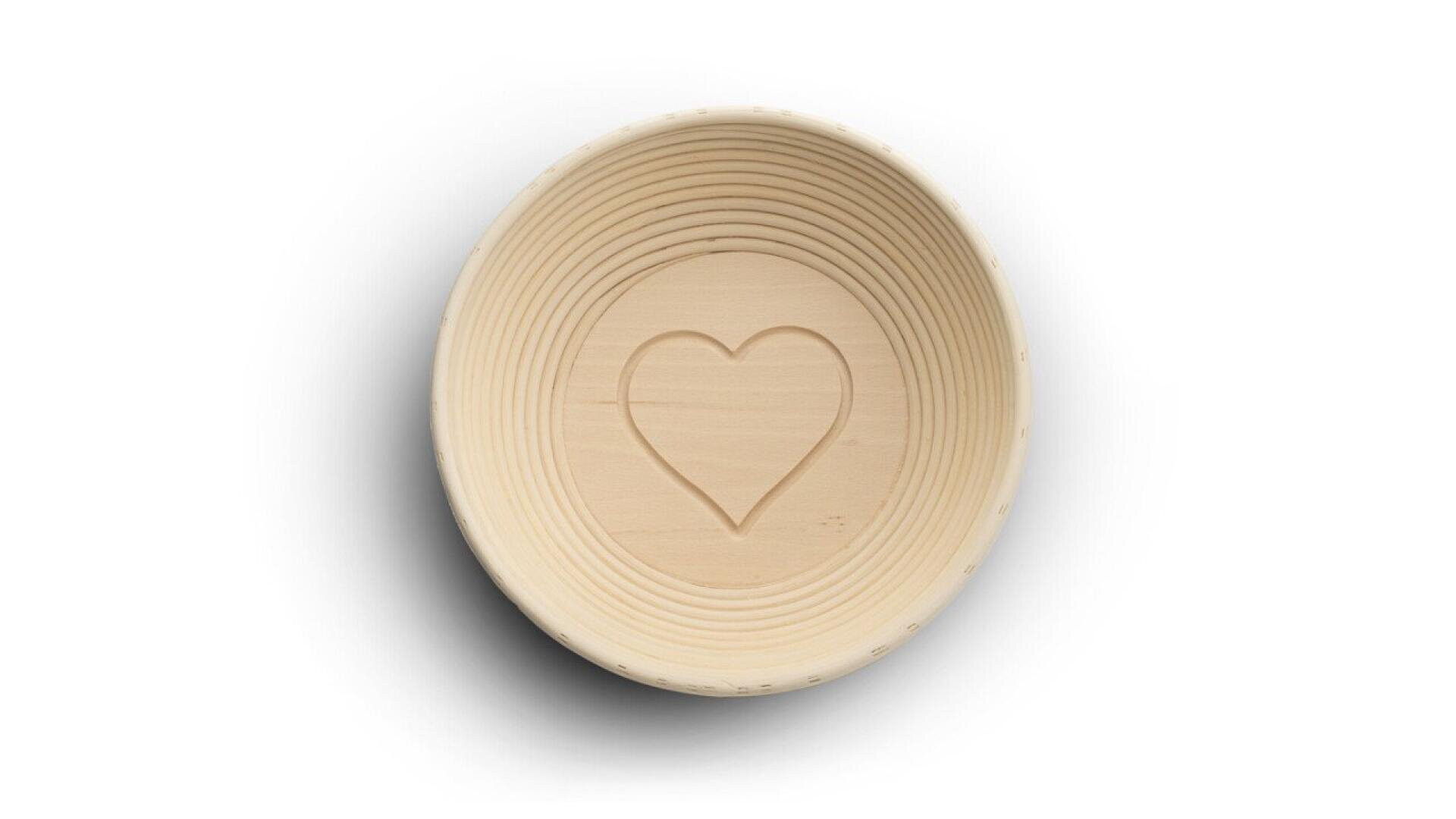 A round, light wooden bowl with concentric grooves and a heart-shaped design carved in the center, photographed from above on a white background.