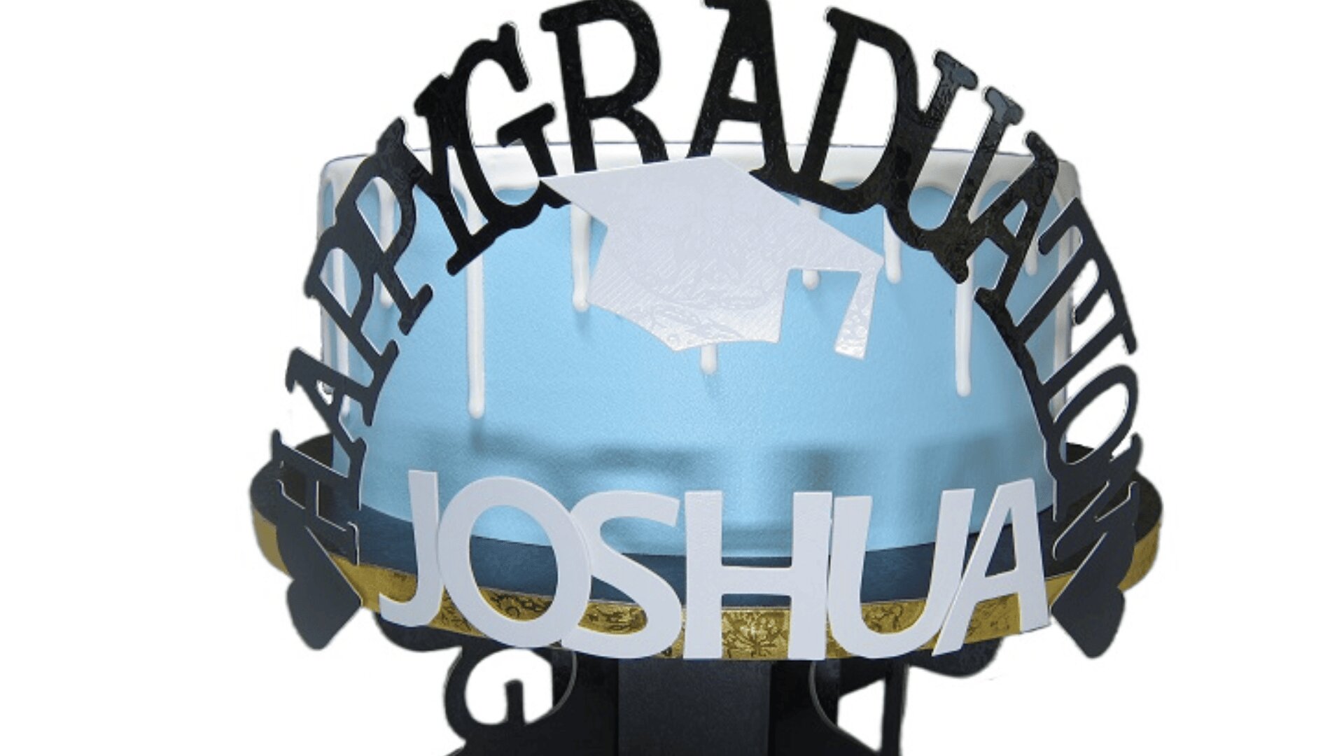 A blue cake with white frosting and a paper graduation cap decoration, featuring the words Happy Graduation JOSHUA displayed around the top.