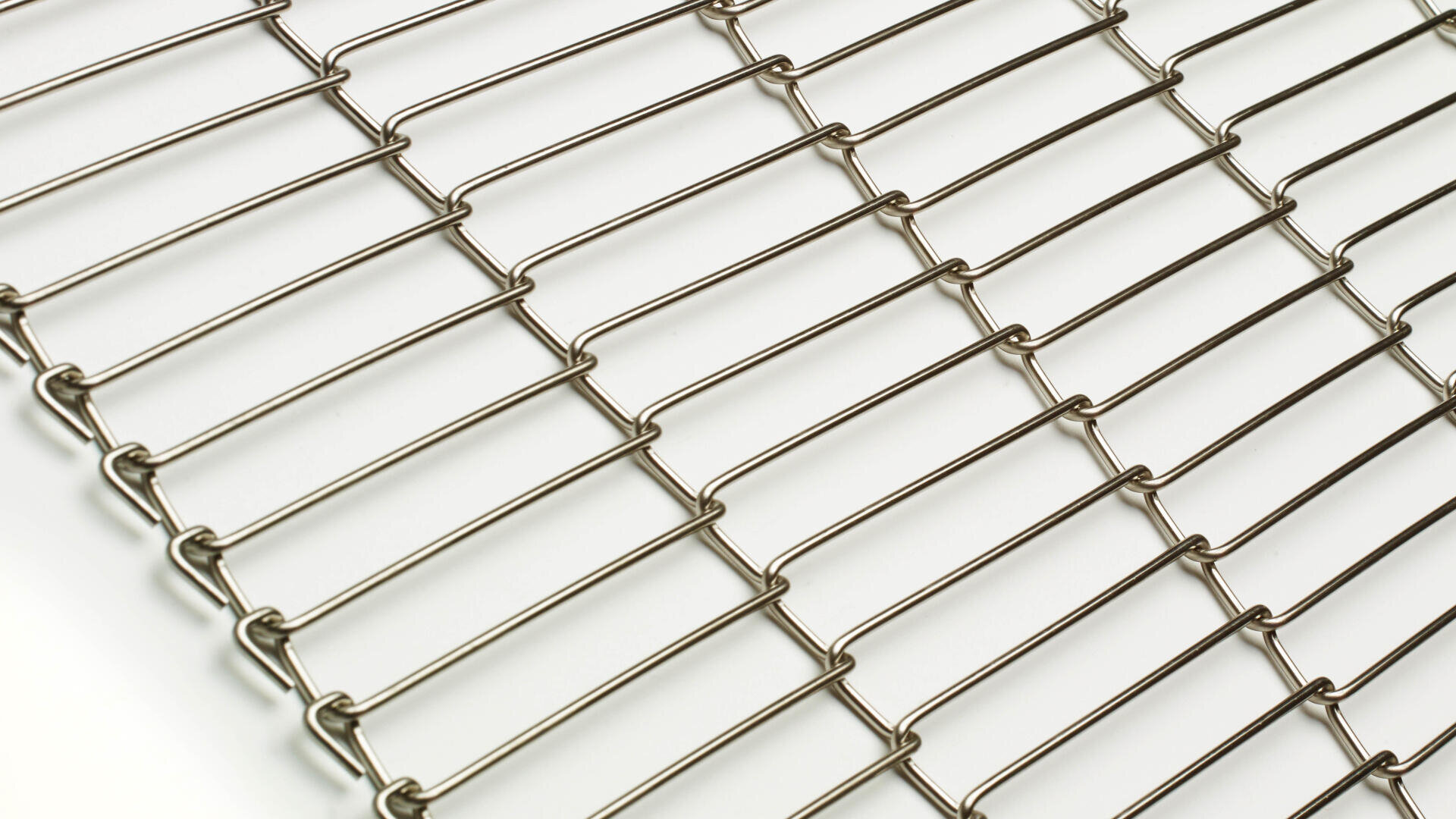 Close-up of a stainless steel wire mesh conveyor belt with parallel horizontal and vertical wires arranged in a grid pattern on a white background.