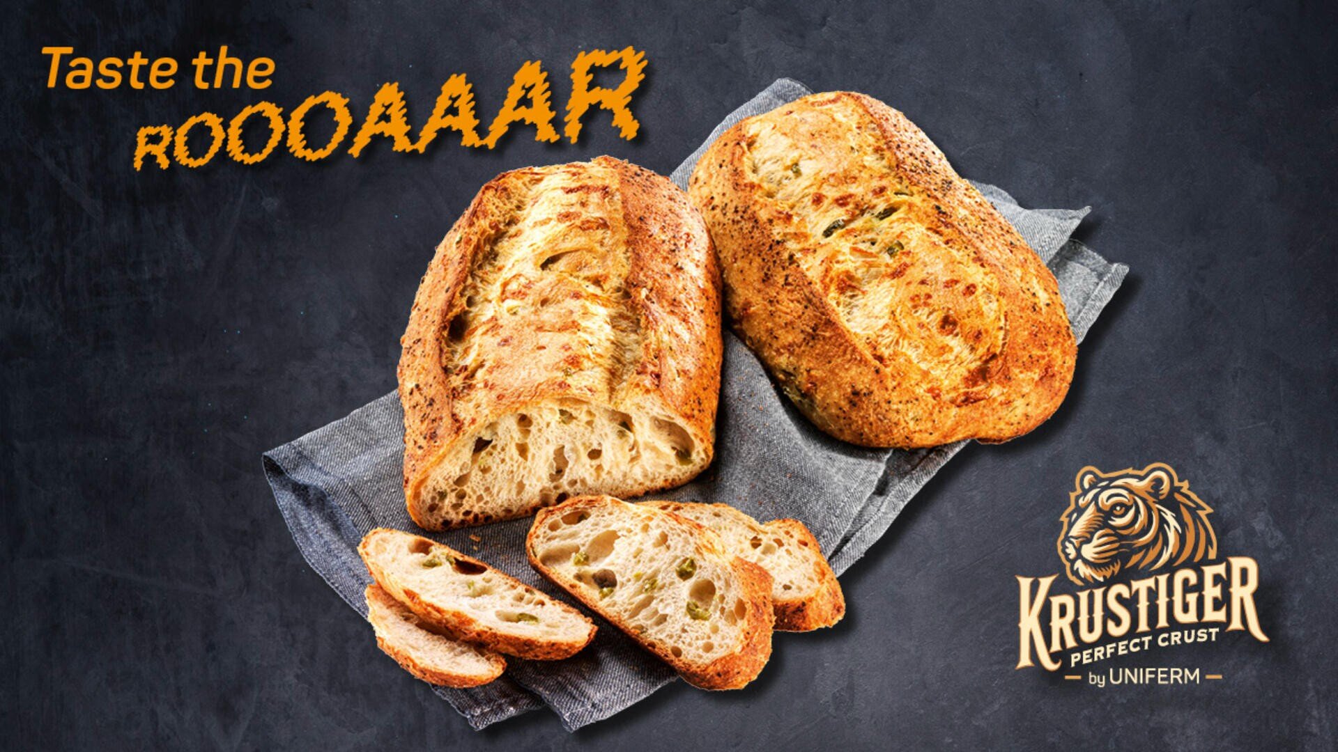 Zwei rustikale Brote, eines davon angeschnitten, liegen auf einem grauen Tuch vor dunklem Hintergrund. Der orangefarbene Text lautet „Taste the ROOOAAAR“. In der Ecke erscheinen ein Tiger-Logo und die Worte „Krustiger Perfect Crust von Uniferm“.