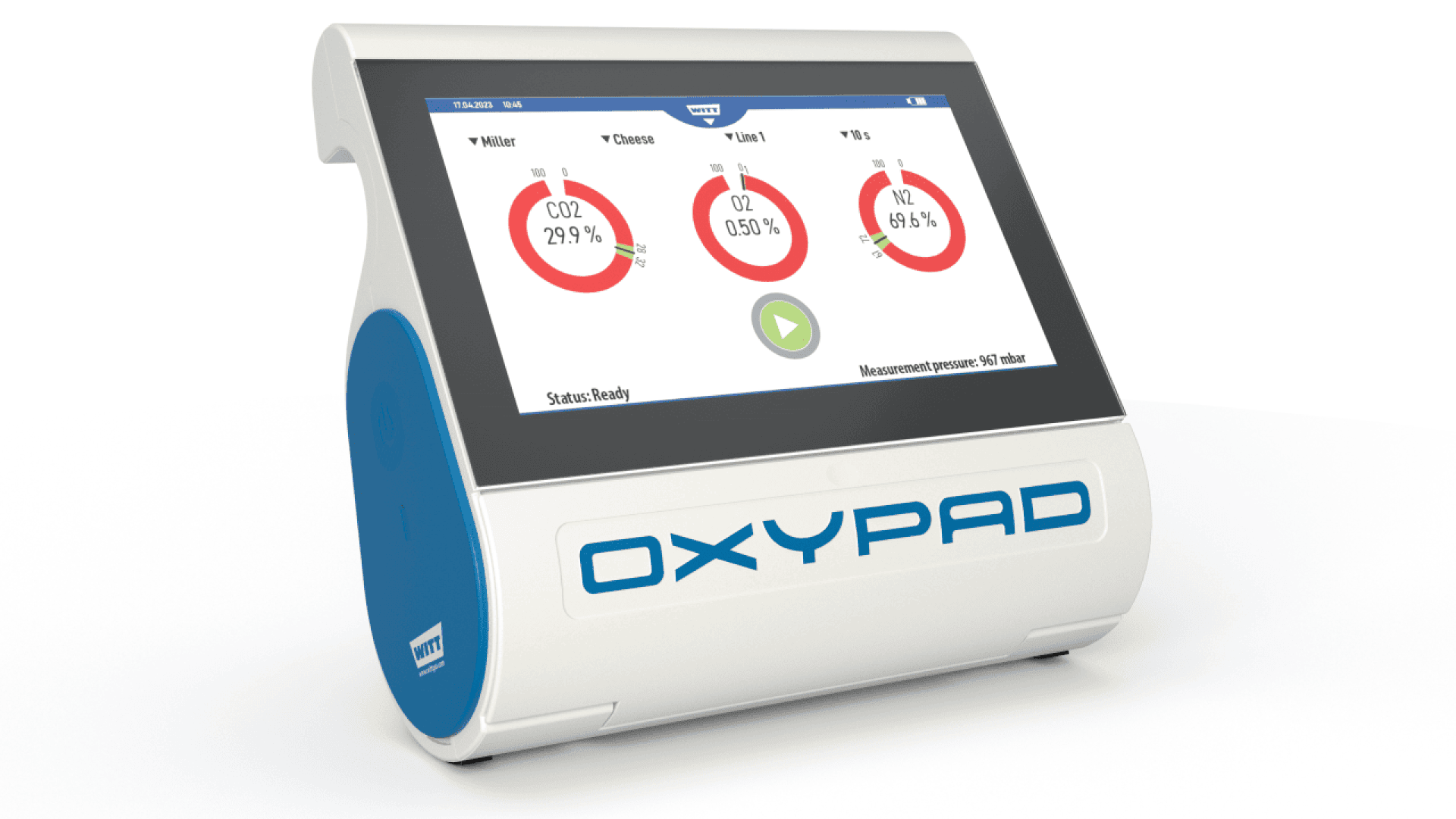 A white and blue device labeled OXY PAD displays gas measurement readings for CO₂, O₂, and N₂ on a touchscreen interface, with digital dials and a green play button on the screen.