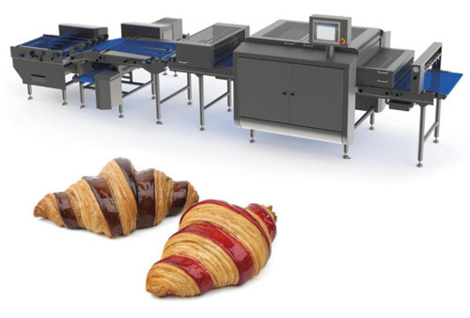 Behind two croissants with chocolate and fruit filling on a white background, a modern industrial machine for making pastries can be seen.