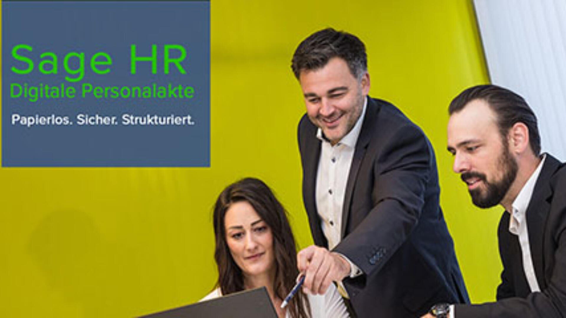 Three business professionals, two men and one woman, discuss something on a laptop in an office with a bright yellow wall. A text box reads, Sage HR Digitale Personalakte. Papierlos. Sicher. Strukturiert.