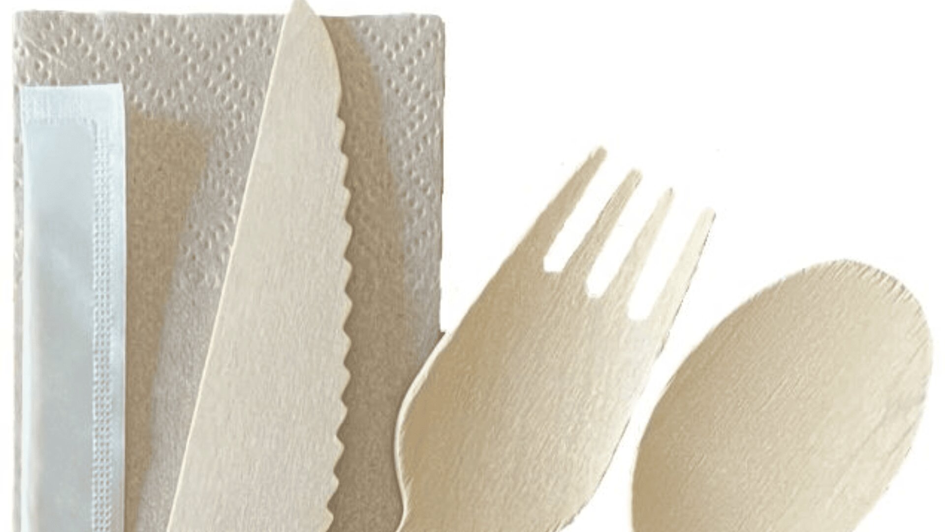 A set of beige disposable cutlery—knife, fork, and spoon—lies on top of a paper napkin and a small packaged item, all against a white background.